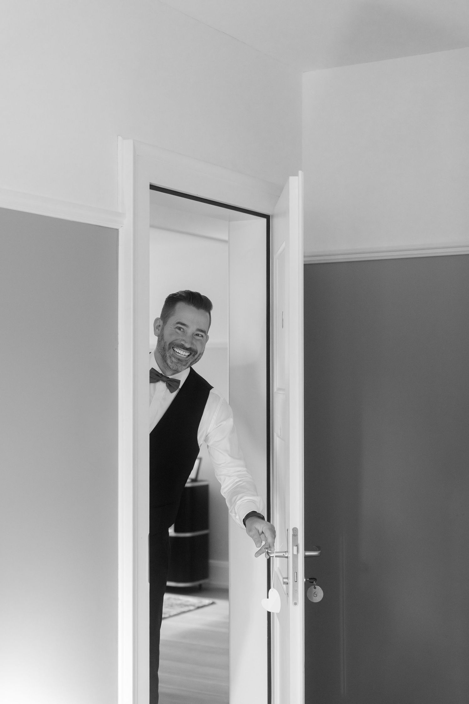 A sequence of four black and white photos showing someone playfully peeking through a doorway at different angles.