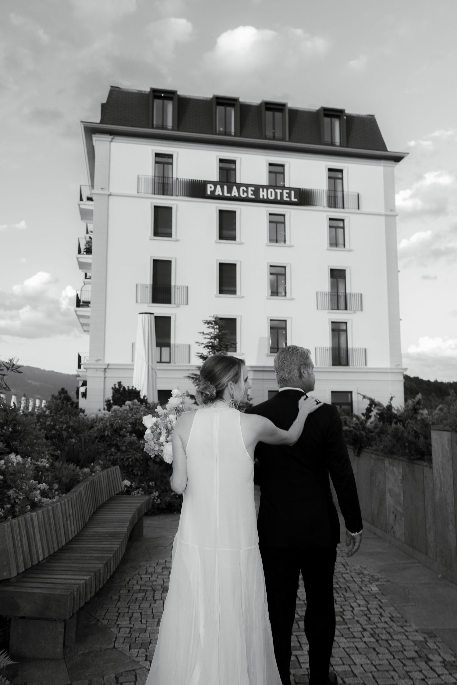 Black and white photo of a bride and groom standing before the Palace Hotel on their wedding day.