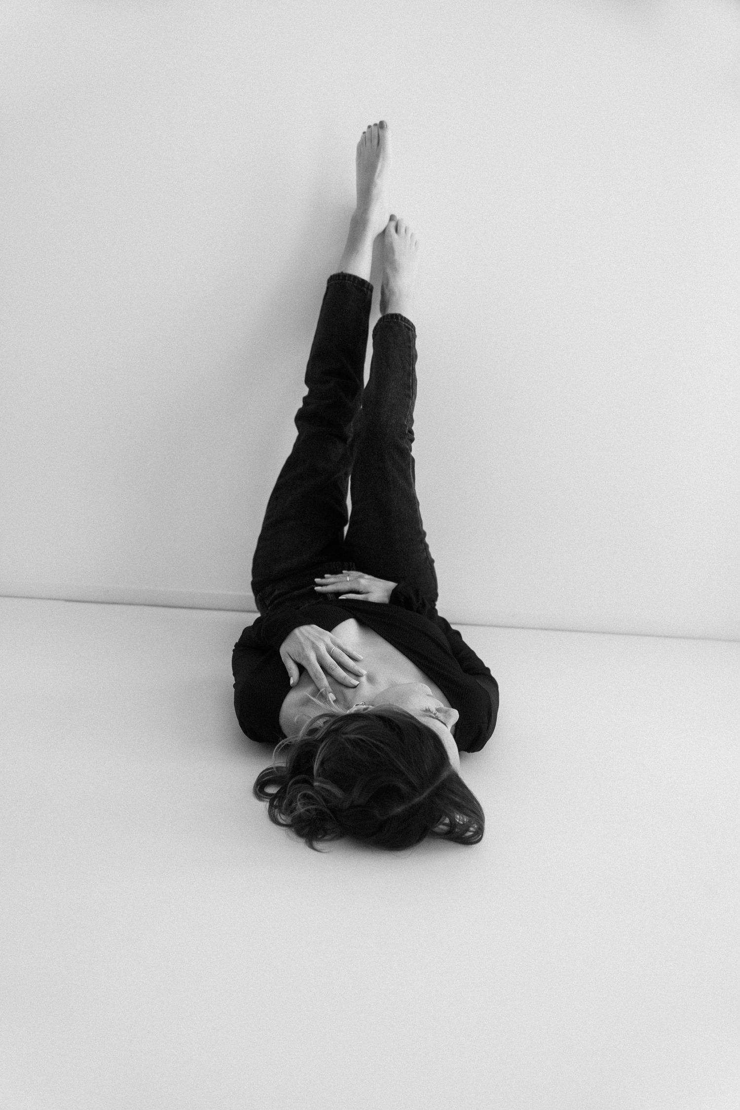 A sequence of black and white photos showing a person in dark clothing rolling across a white floor.