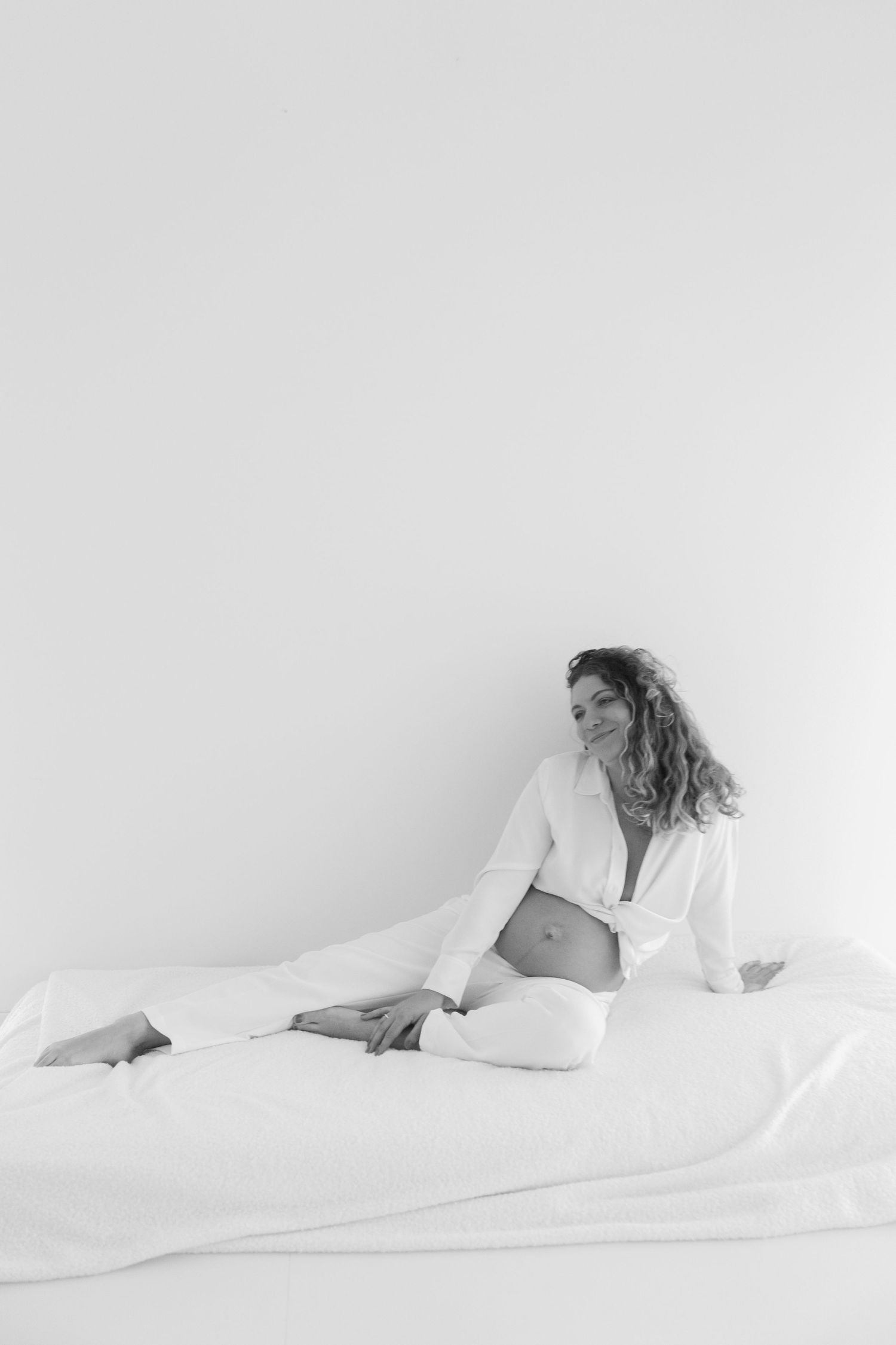 Three minimalist black and white photos show a figure resting under crisp white bedding in a peaceful composition.