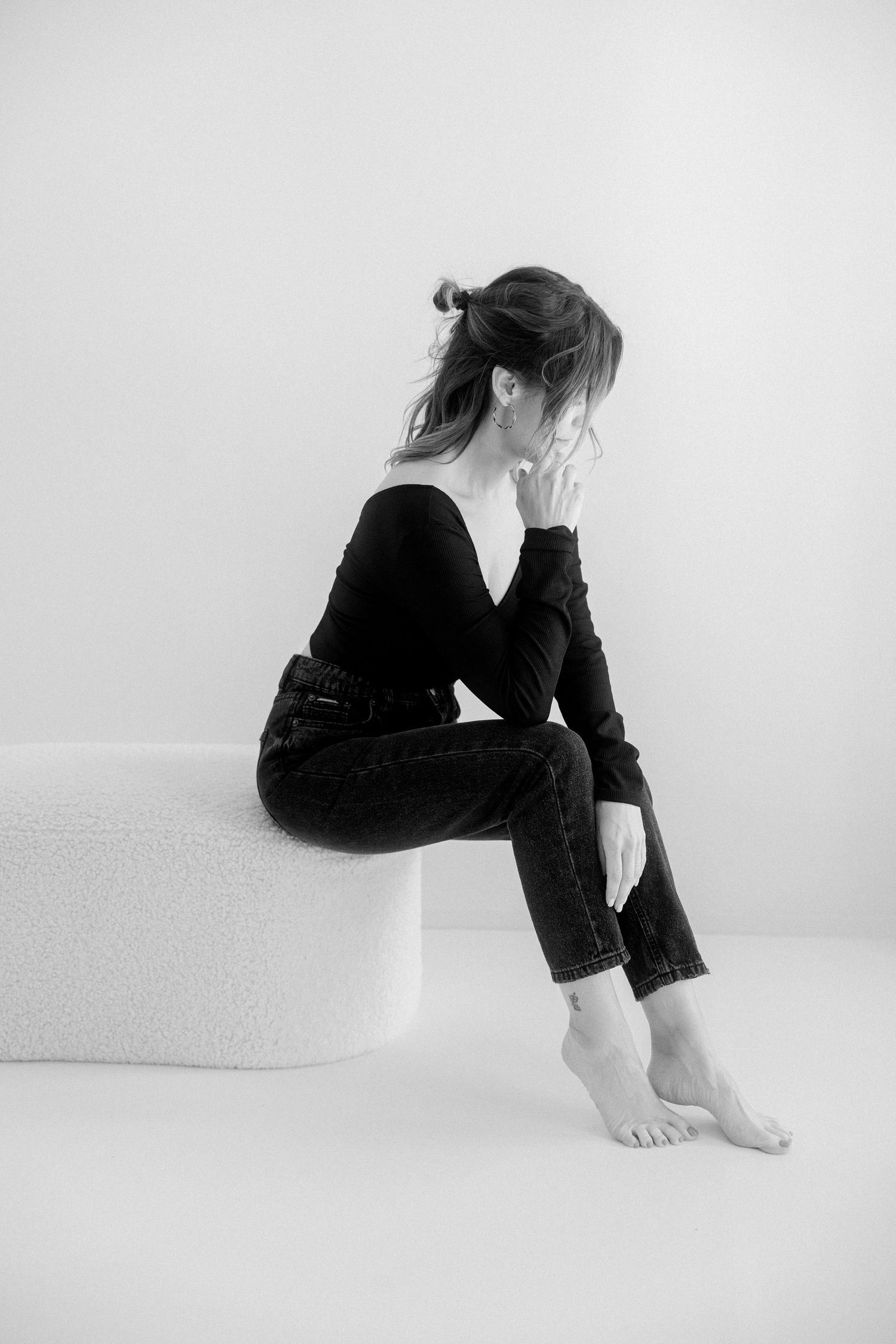 A series of black and white artistic photographs showing a person in dark clothing sitting in contemplative poses.