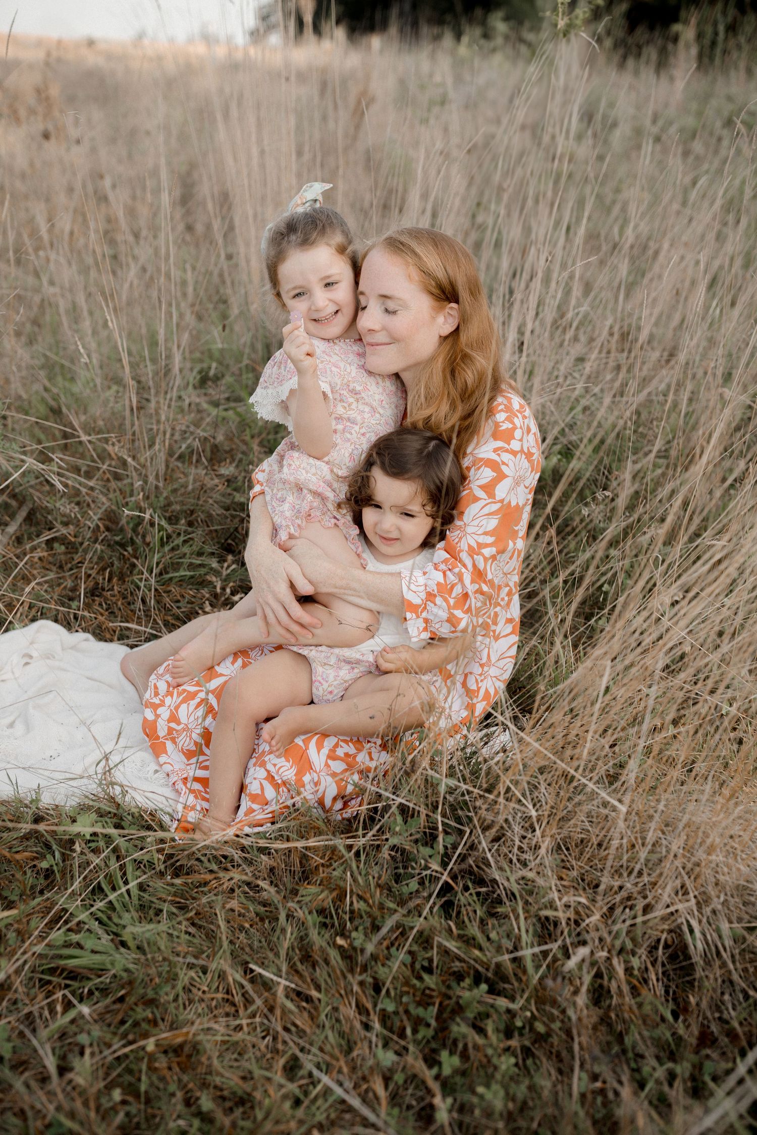 Family portrait in tall grass during golden hour wearing coordinated floral outfits.