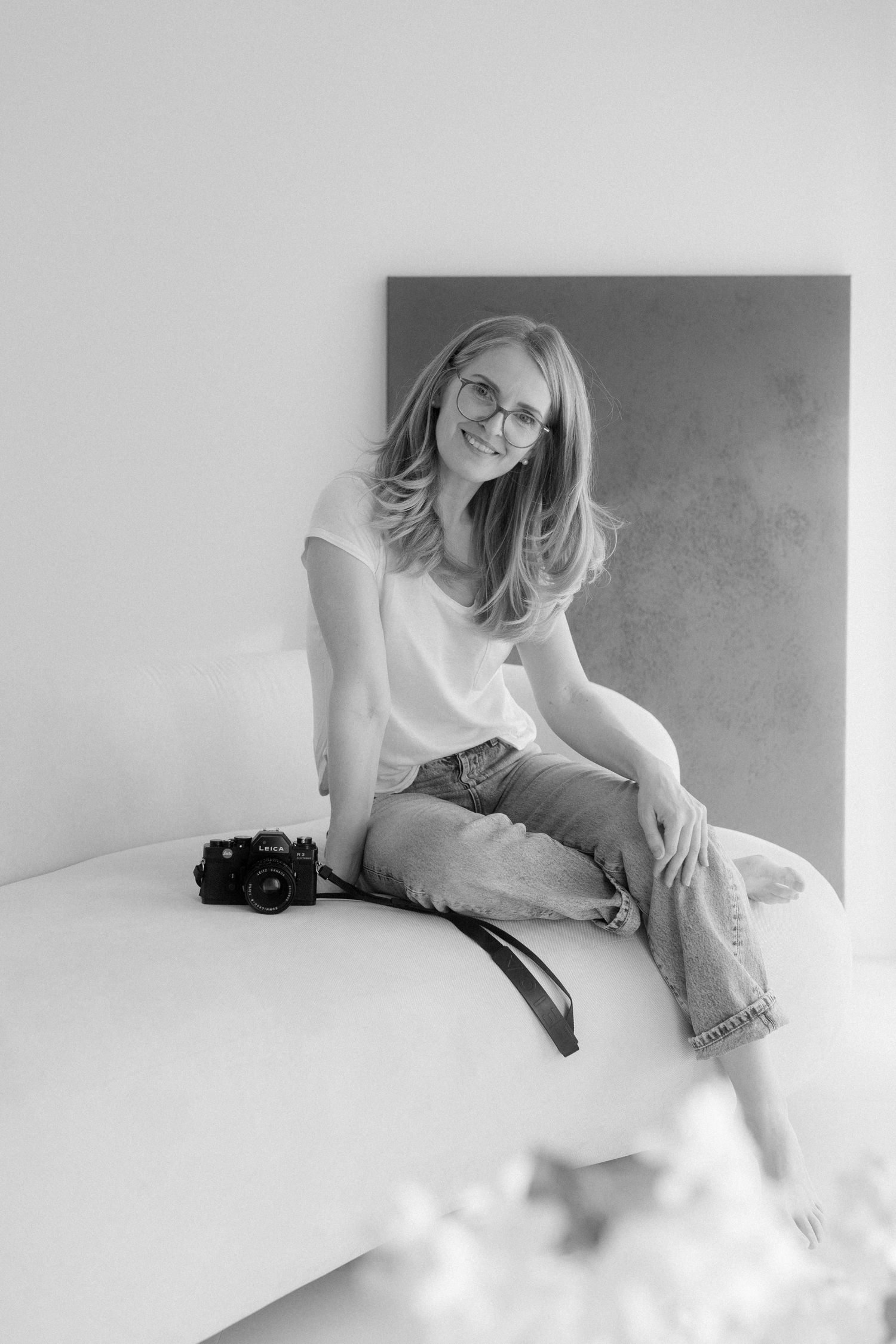 Artistic black and white portrait session with vintage camera on white backdrop.