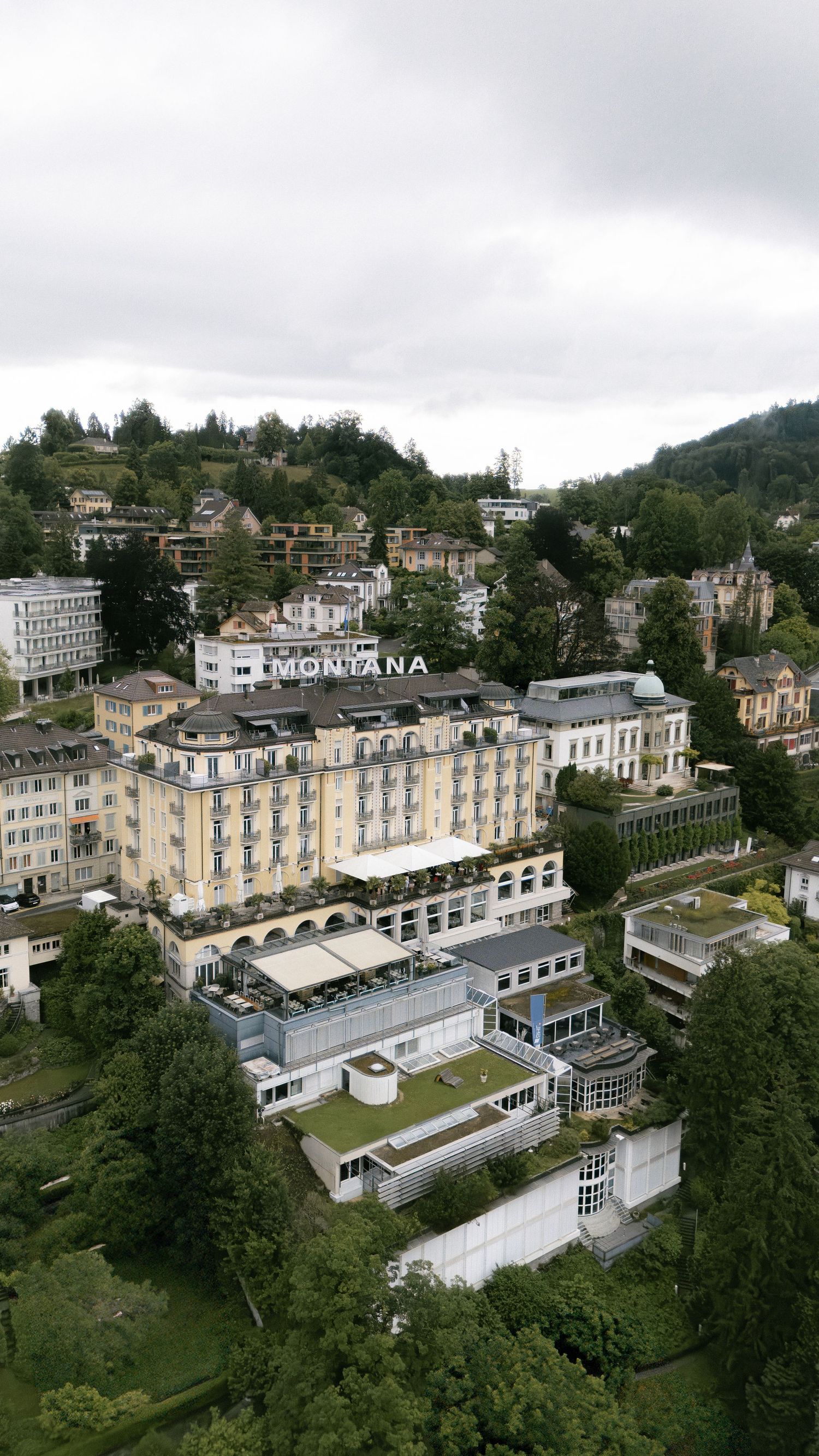 Aerial view of the grand Montana Hotel nestled in a hillside surrounded by trees and buildings.