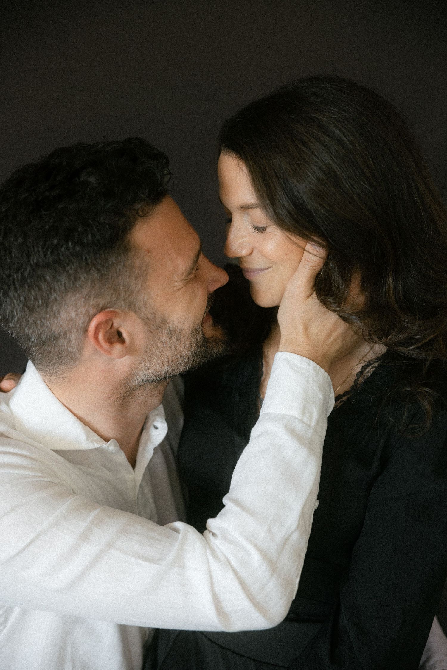 A romantic sequence showing a couple in white and black attire drawing closer together against a dark background.