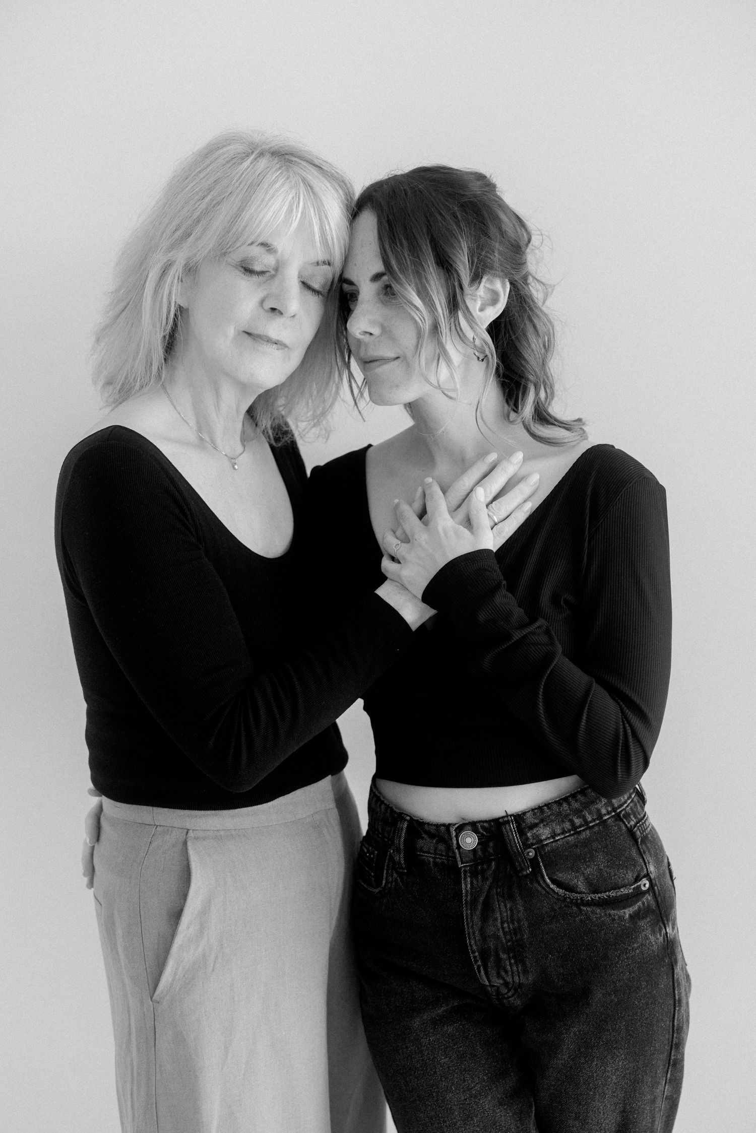 Black and white artistic portrait series showing two figures in black clothing interacting against a light background.