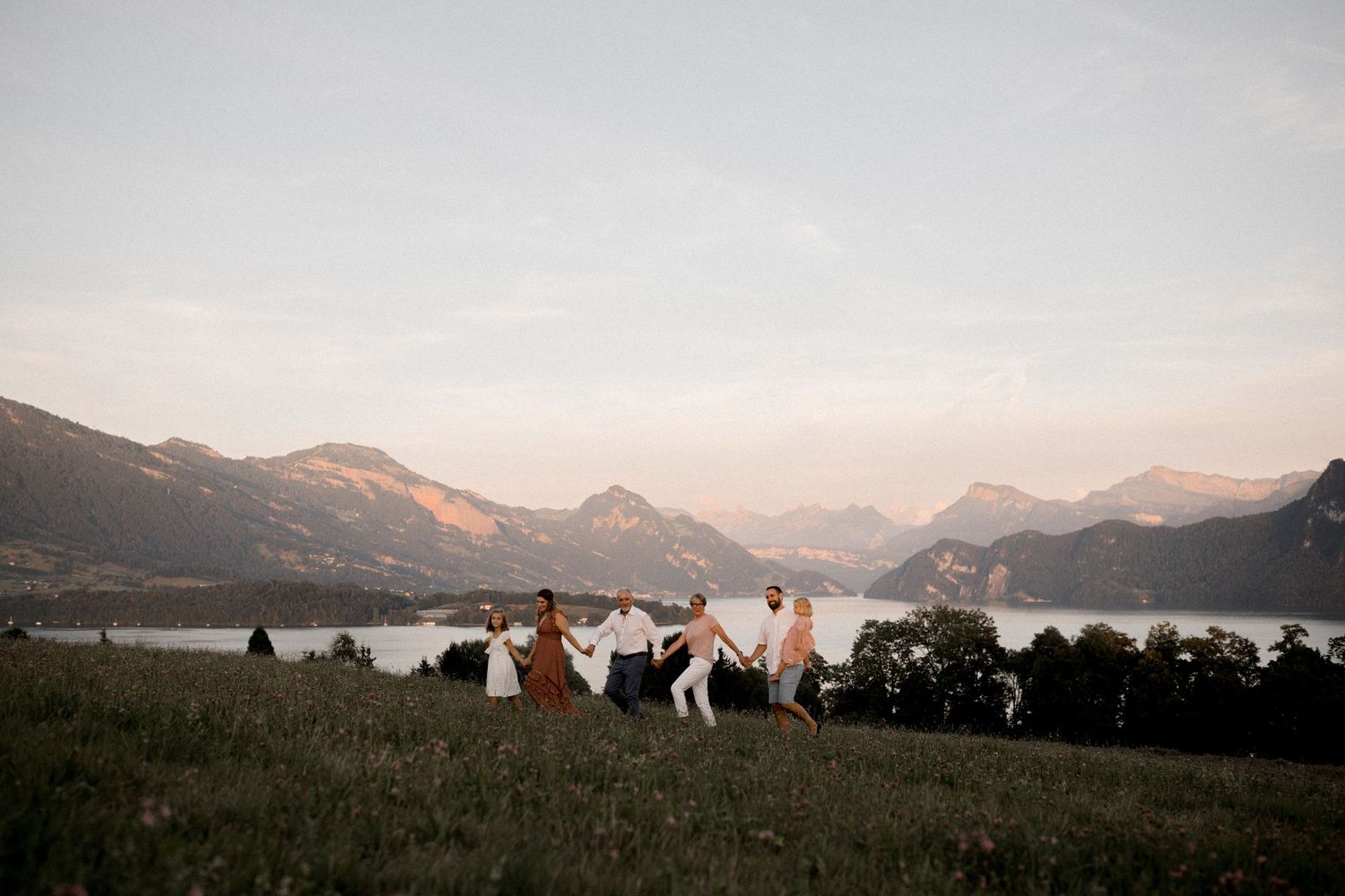 Panoramic mountain landscape with distant figures silhouetted against a sunset sky.