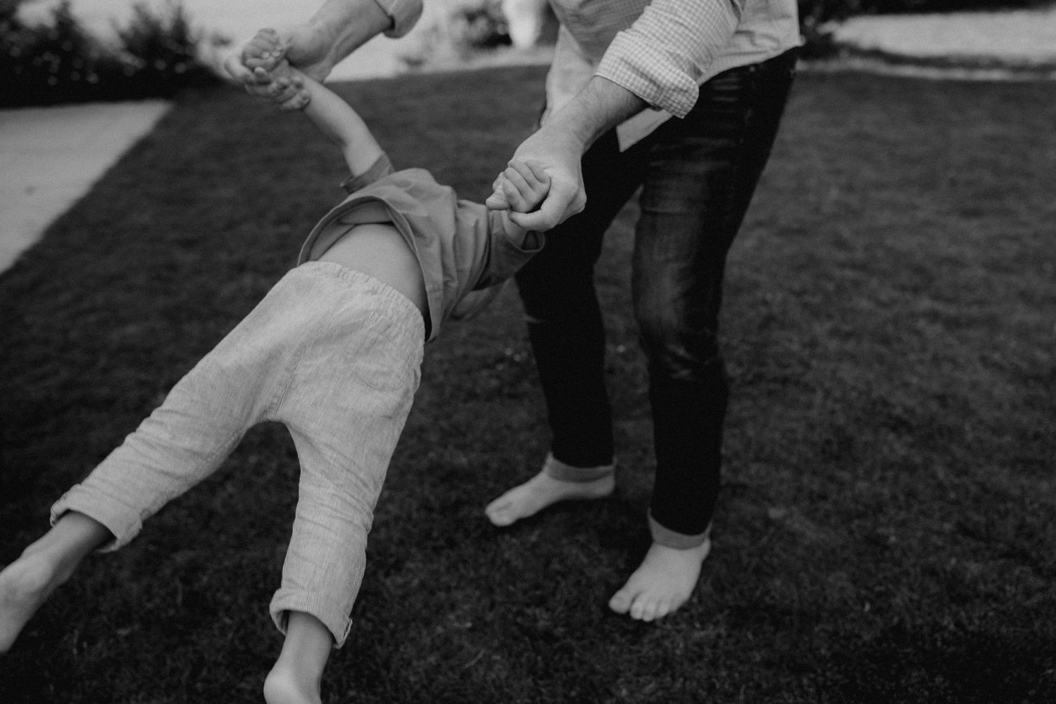 Low-angle view of people's legs and feet playing together on grass.