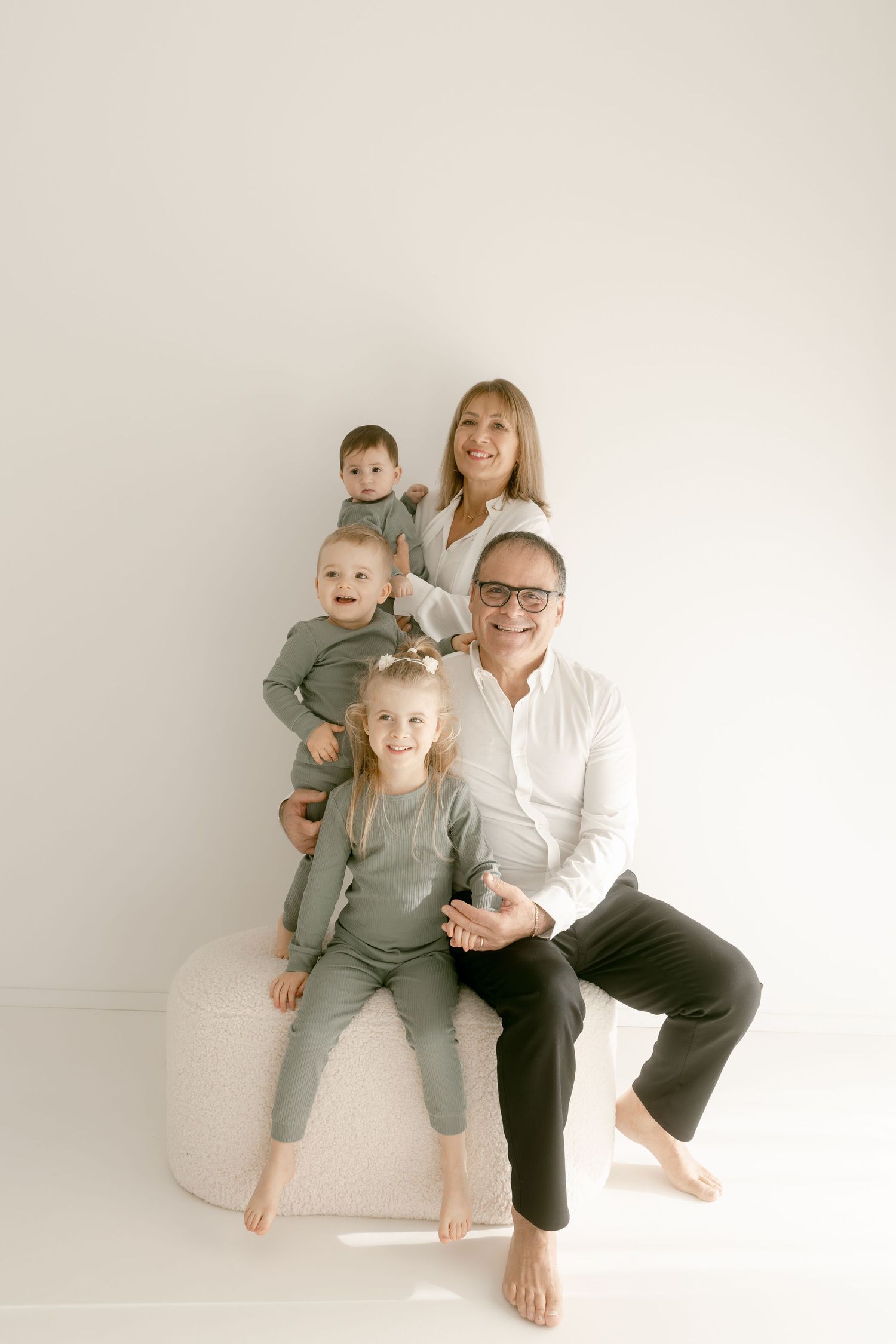 Casual family studio portraits with everyone wearing coordinated outfits against a cream background.