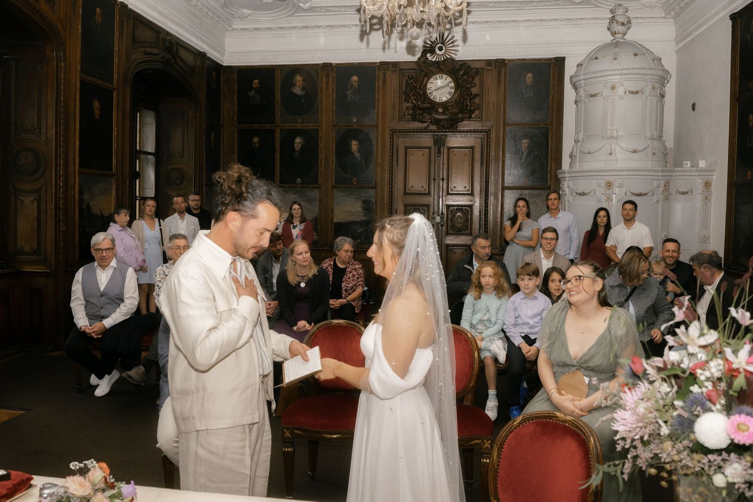 Couple exchanging vows at an elegant indoor wedding ceremony with guests seated in a historic room. Rathaus Luzern