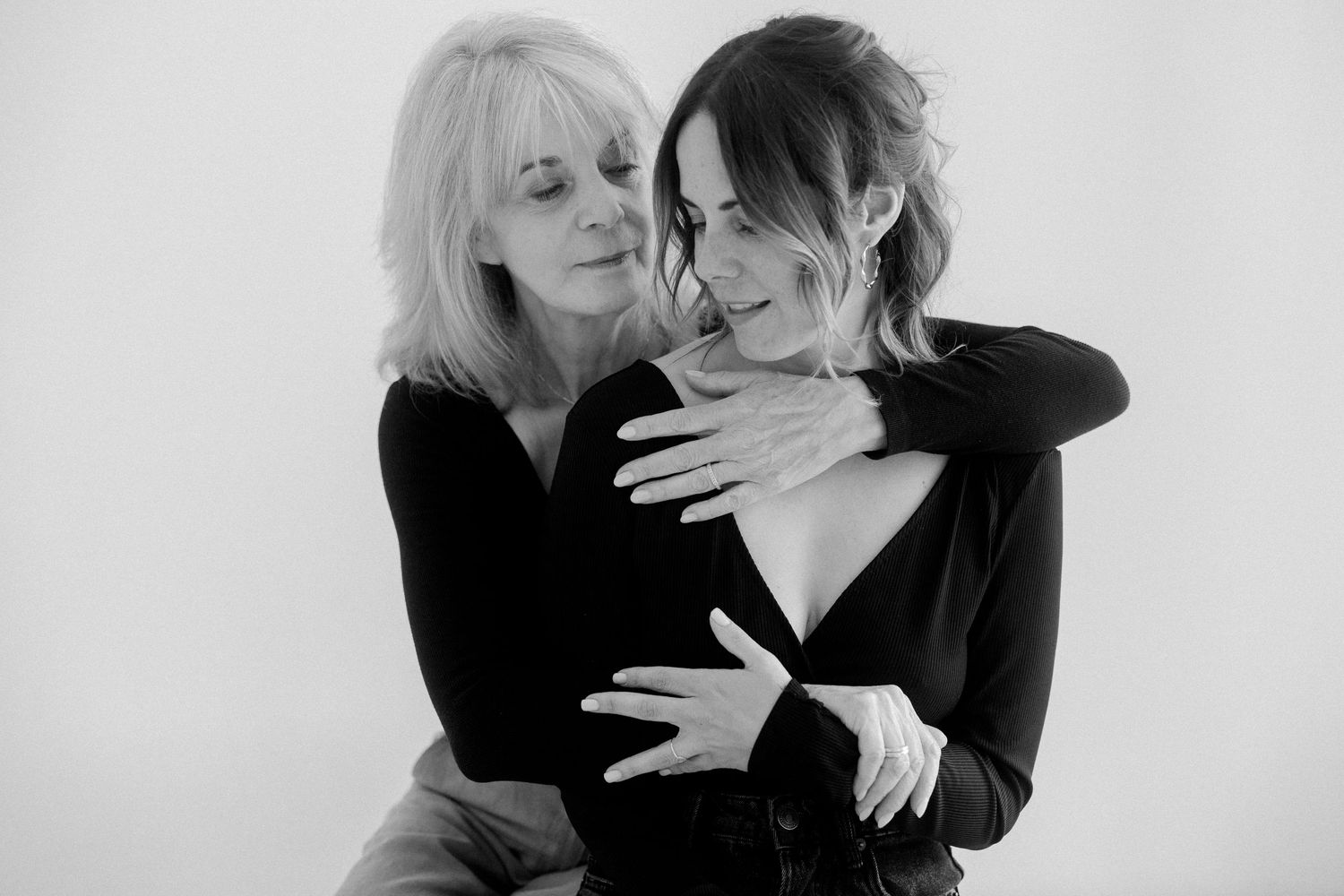 Two people in black clothing embrace intimately in a series of romantic black and white photographs.
