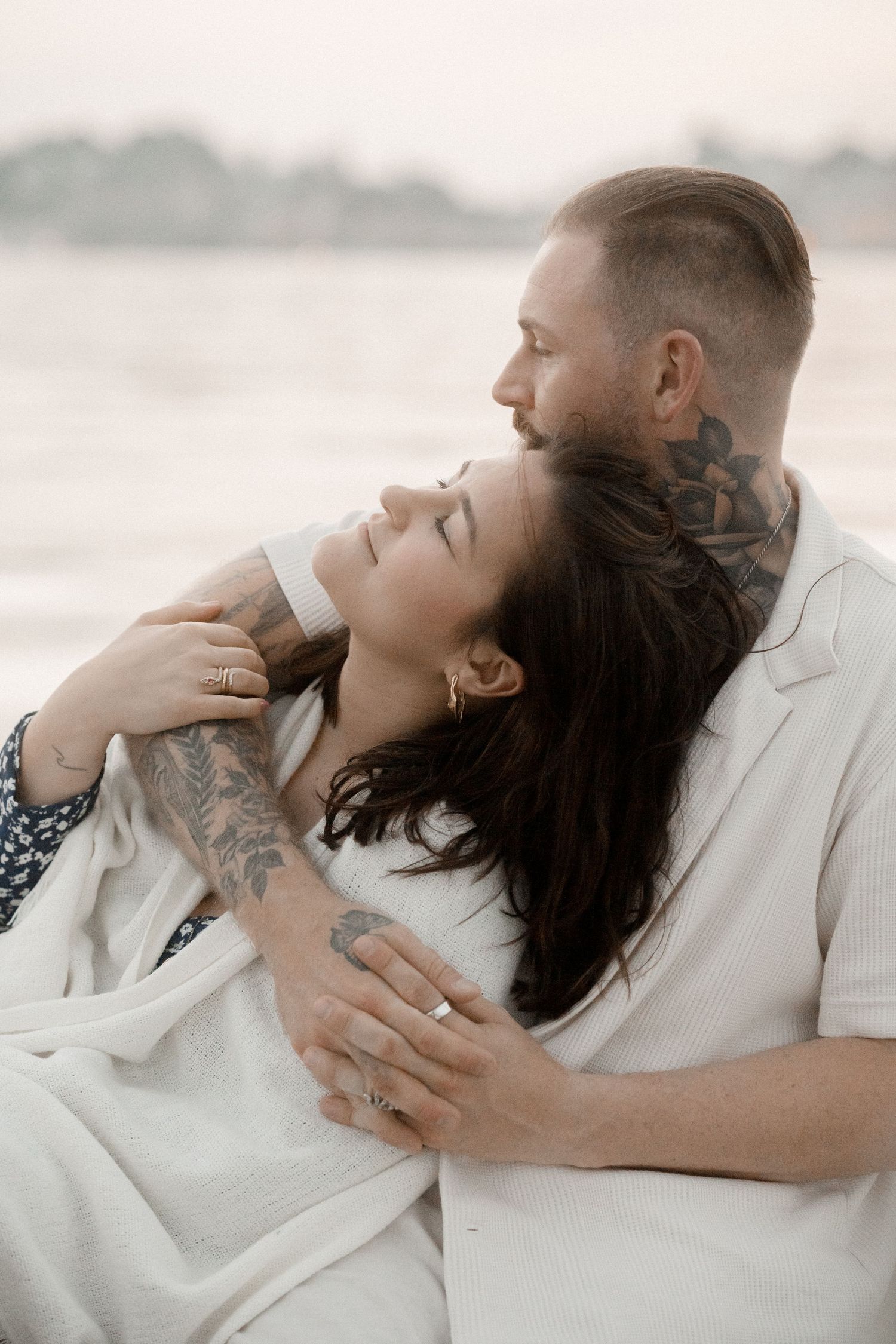 Romantic couple in white embracing on beach in series of intimate black and white photos.