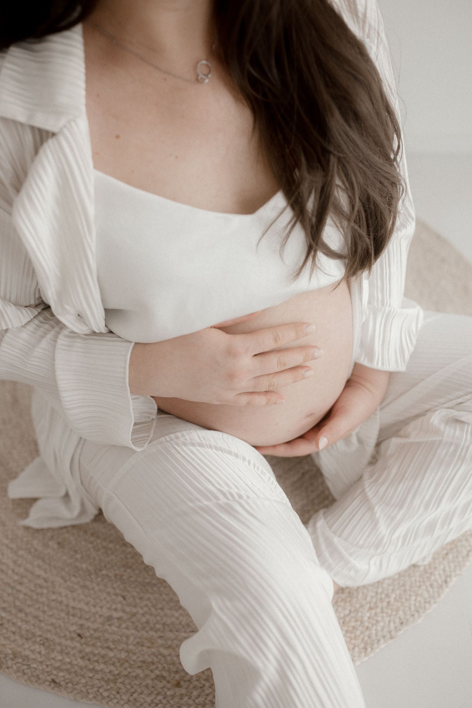 Close-up shots of a pregnant woman in white clothing sitting on textured carpet.