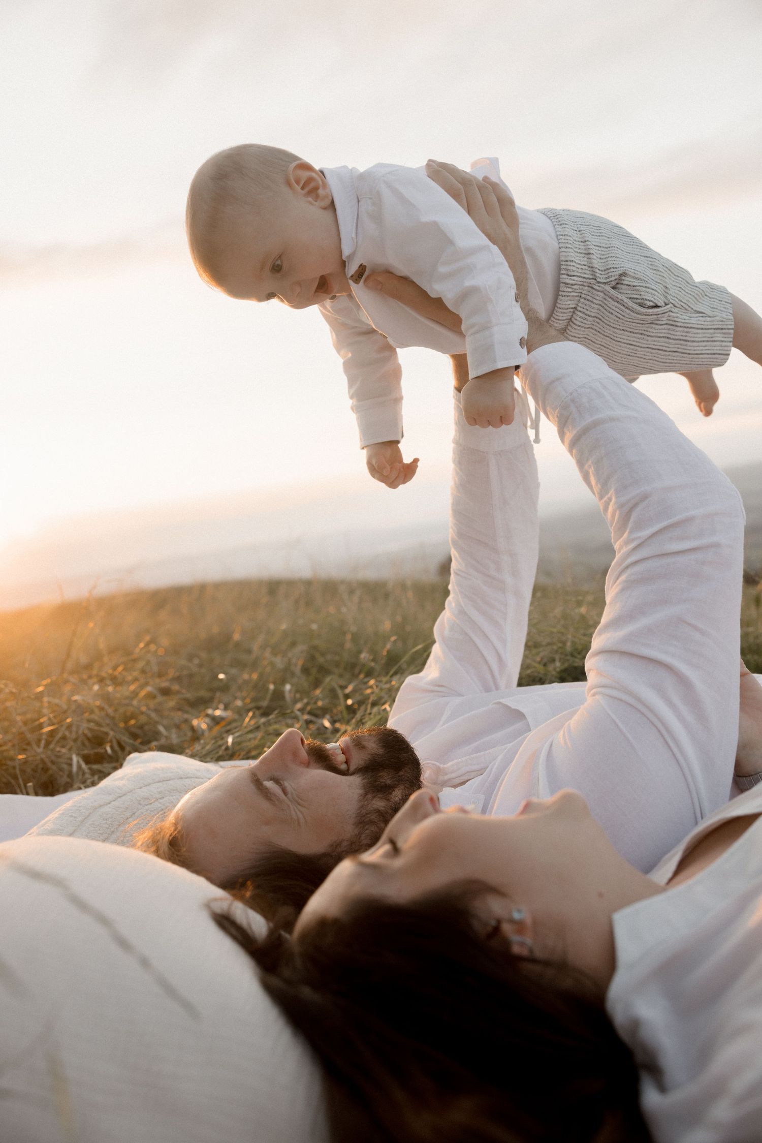 Candid family interaction captured against sunset sky in outdoor setting.
