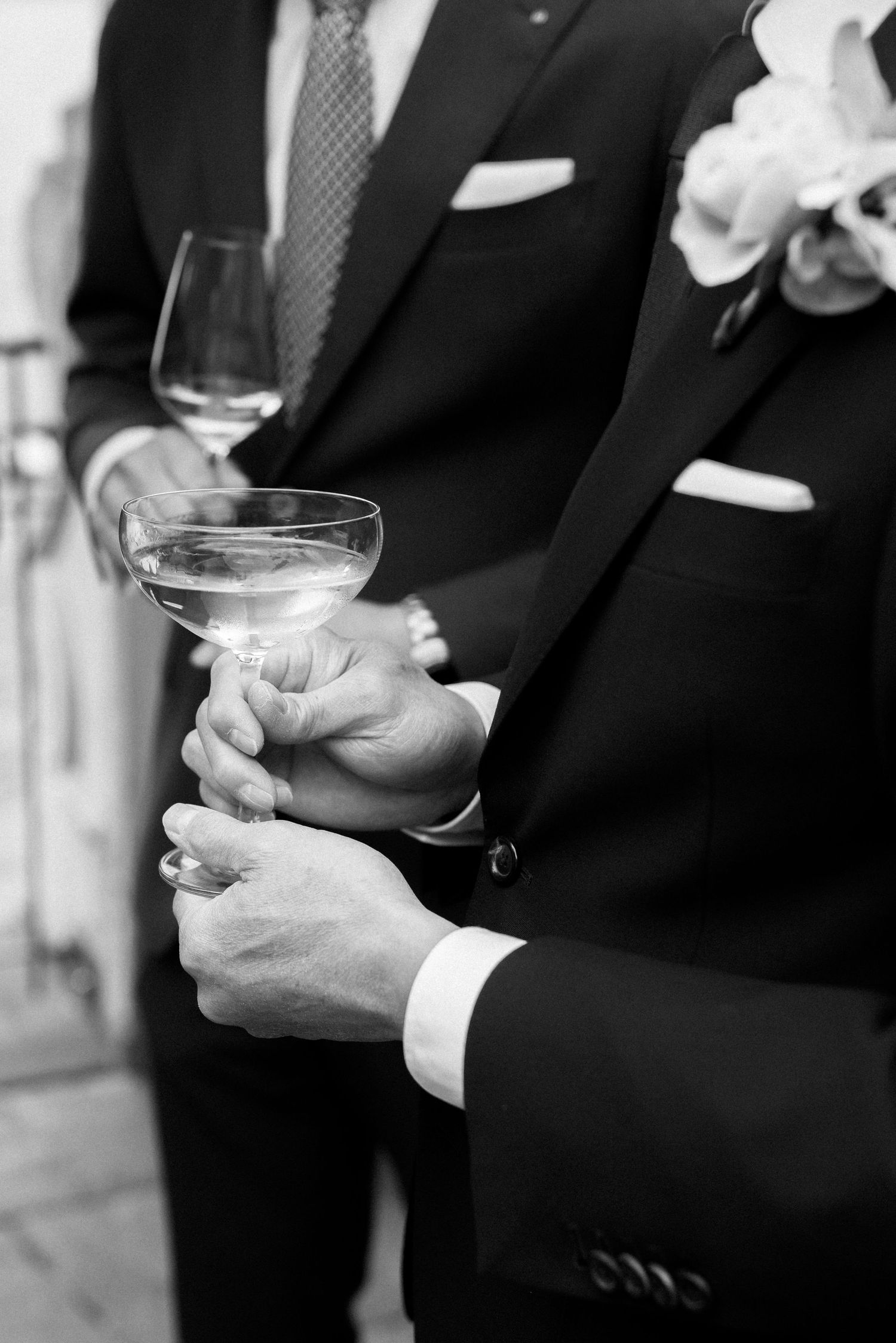 Row of hands holding cocktail glasses at formal event in black and white at Vitznauerhof Luzern.
