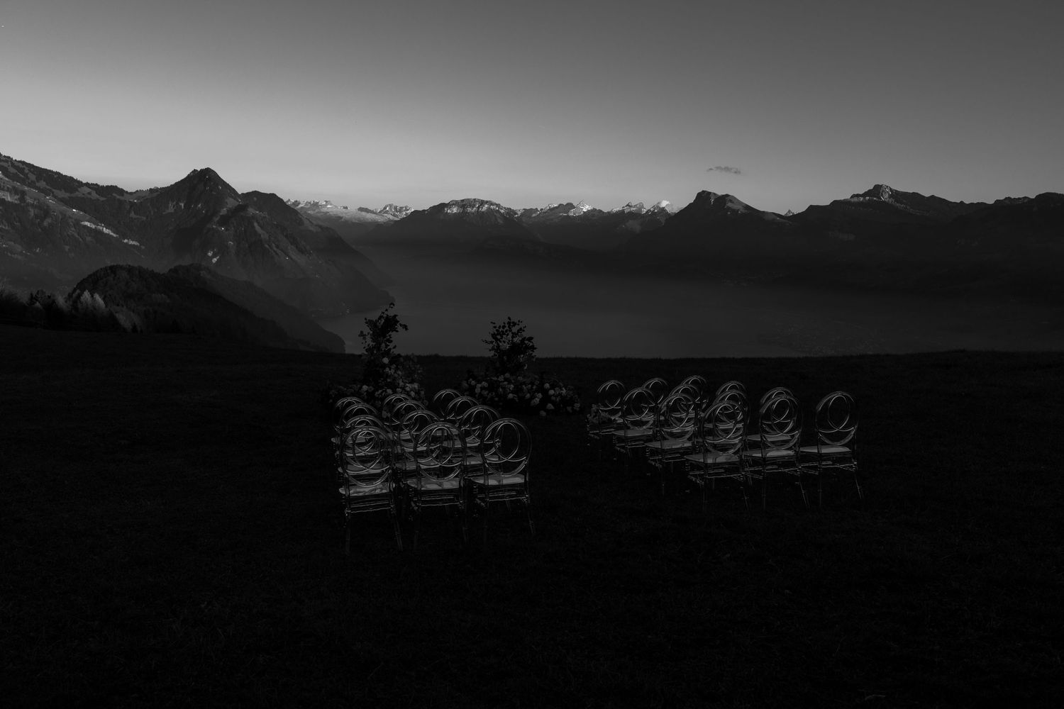 Black and white landscape photograph of mountain silhouettes at dusk with misty valleys and distant peaks at Villa Honegg Bürgenstock