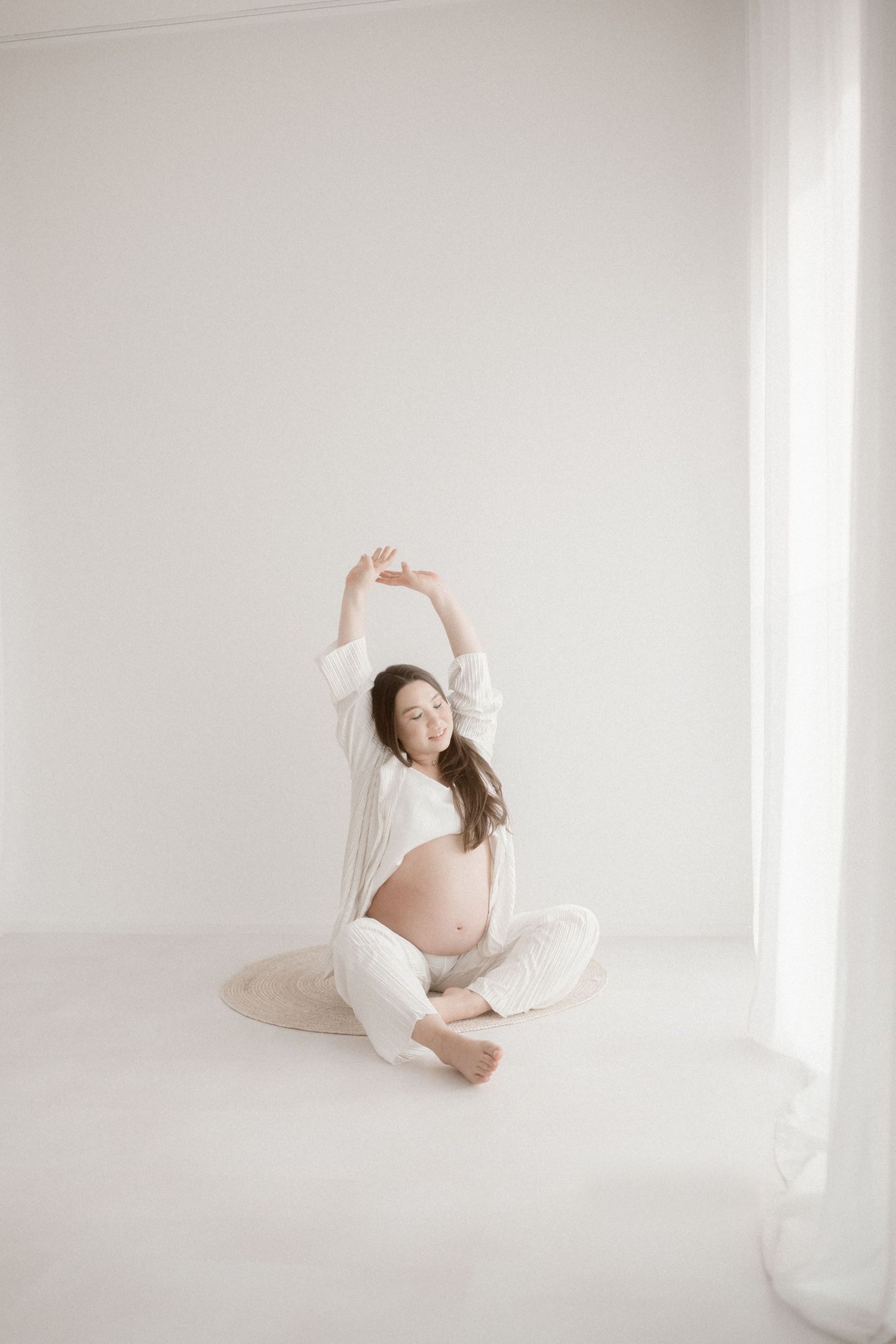 Artistic maternity photos in white studio showing graceful poses against minimal backdrop.