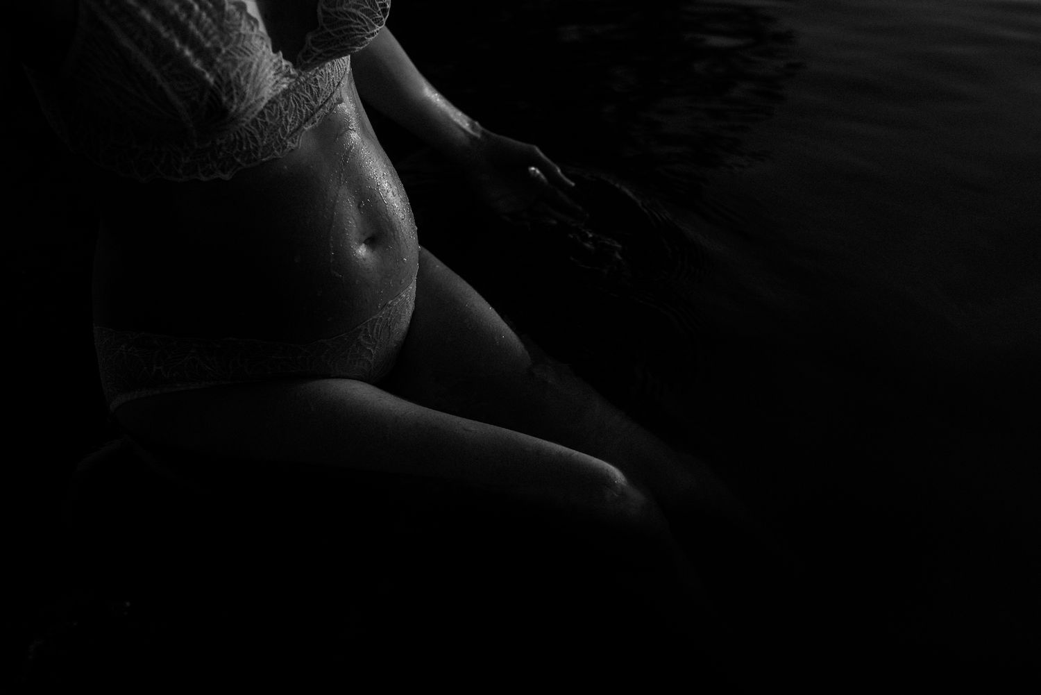 Artistic black and white photo highlighting pregnancy silhouette in dramatic lighting.