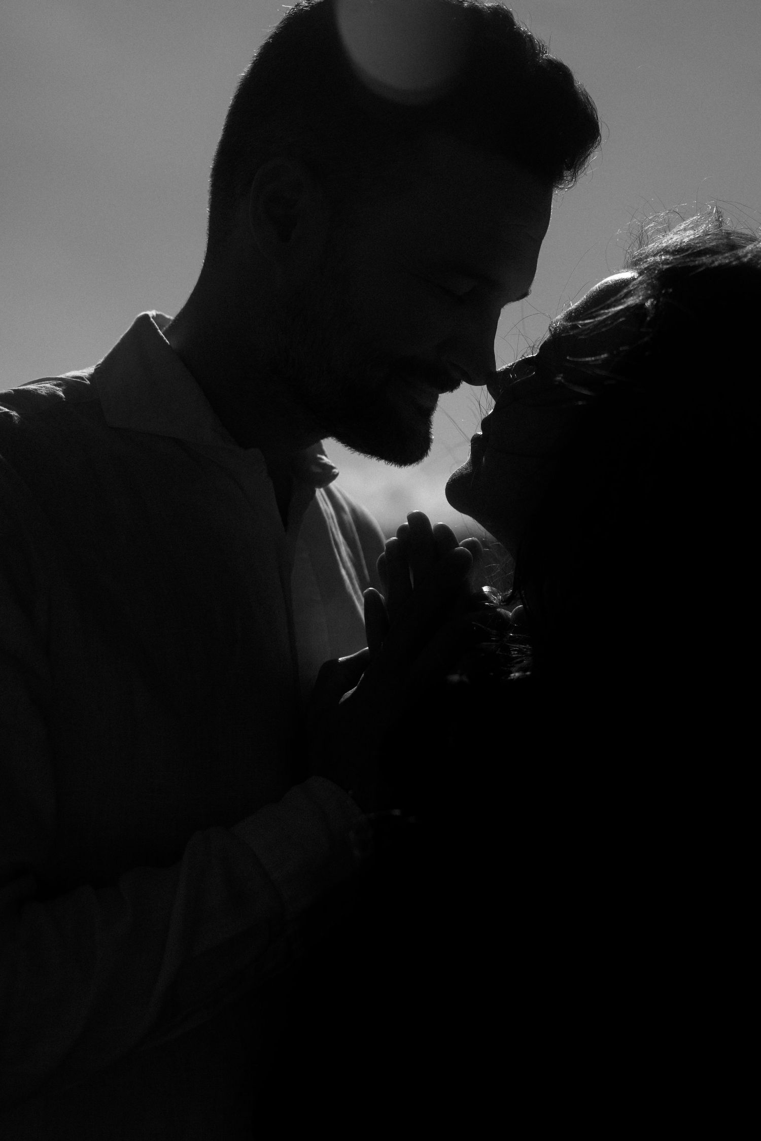 Silhouetted figures in dramatic backlit black and white composition.