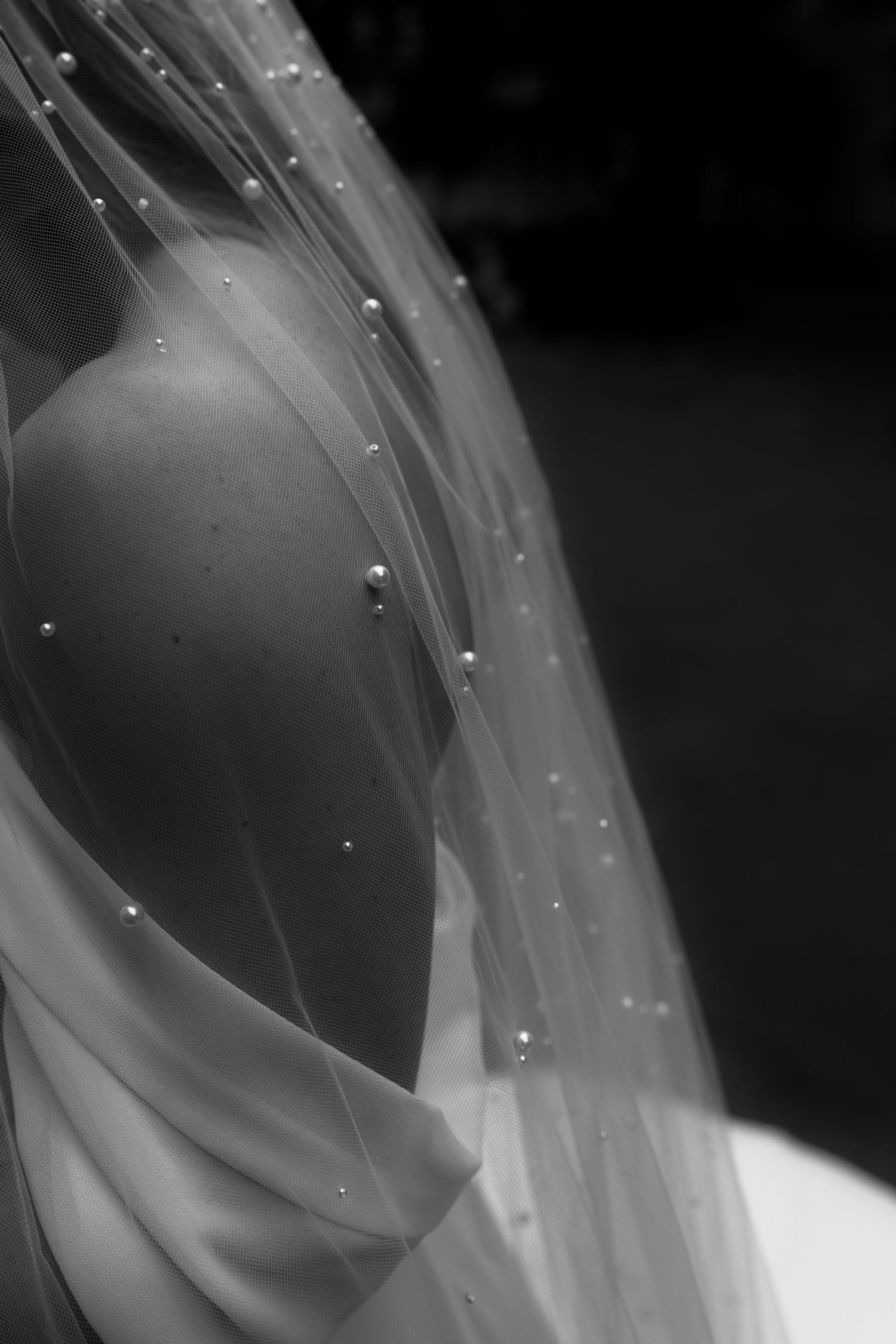 Close-up of delicate beading detail on sheer wedding veil fabric.