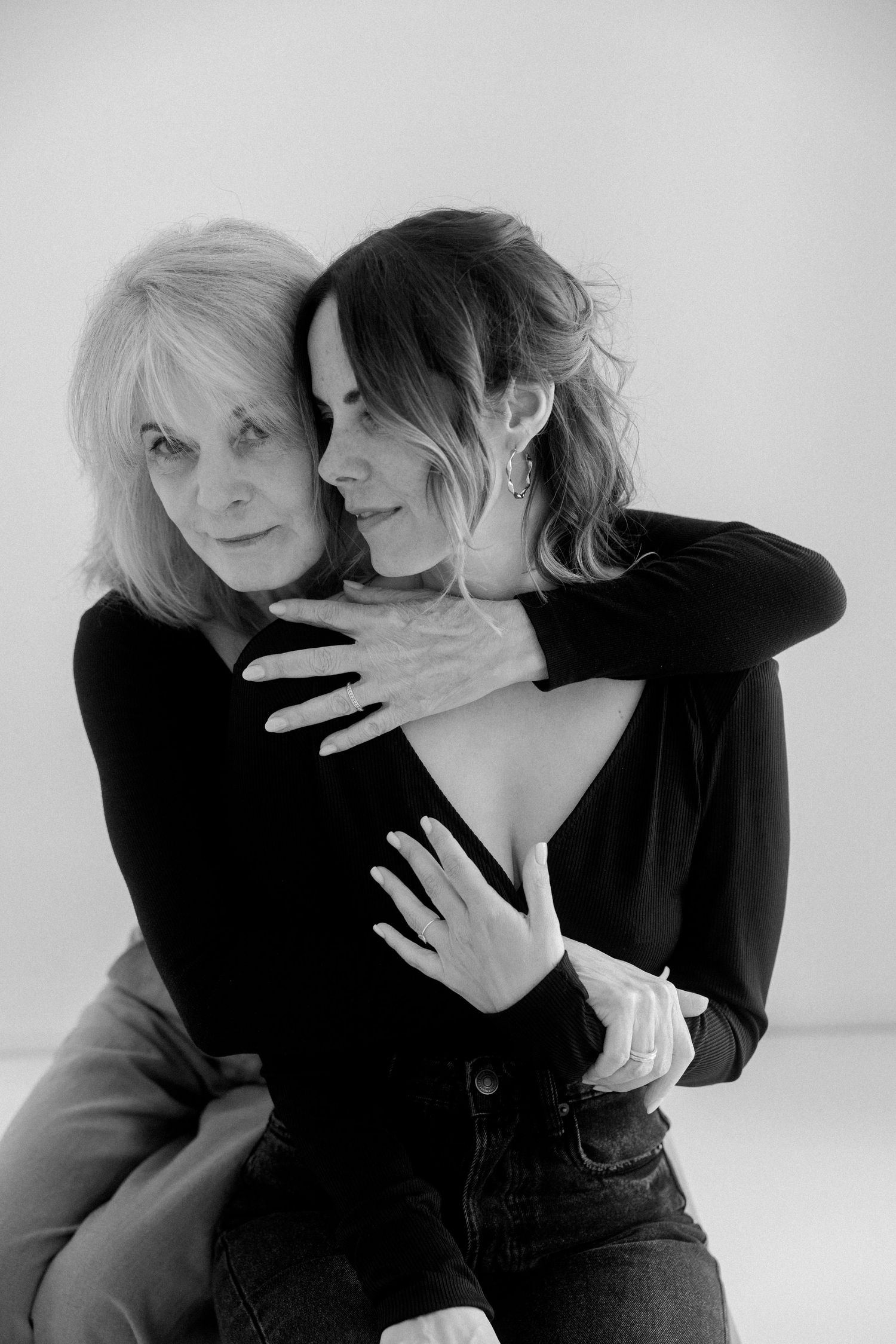 Black and white photo series showing intimate embrace between two people in dark clothing against white background.
