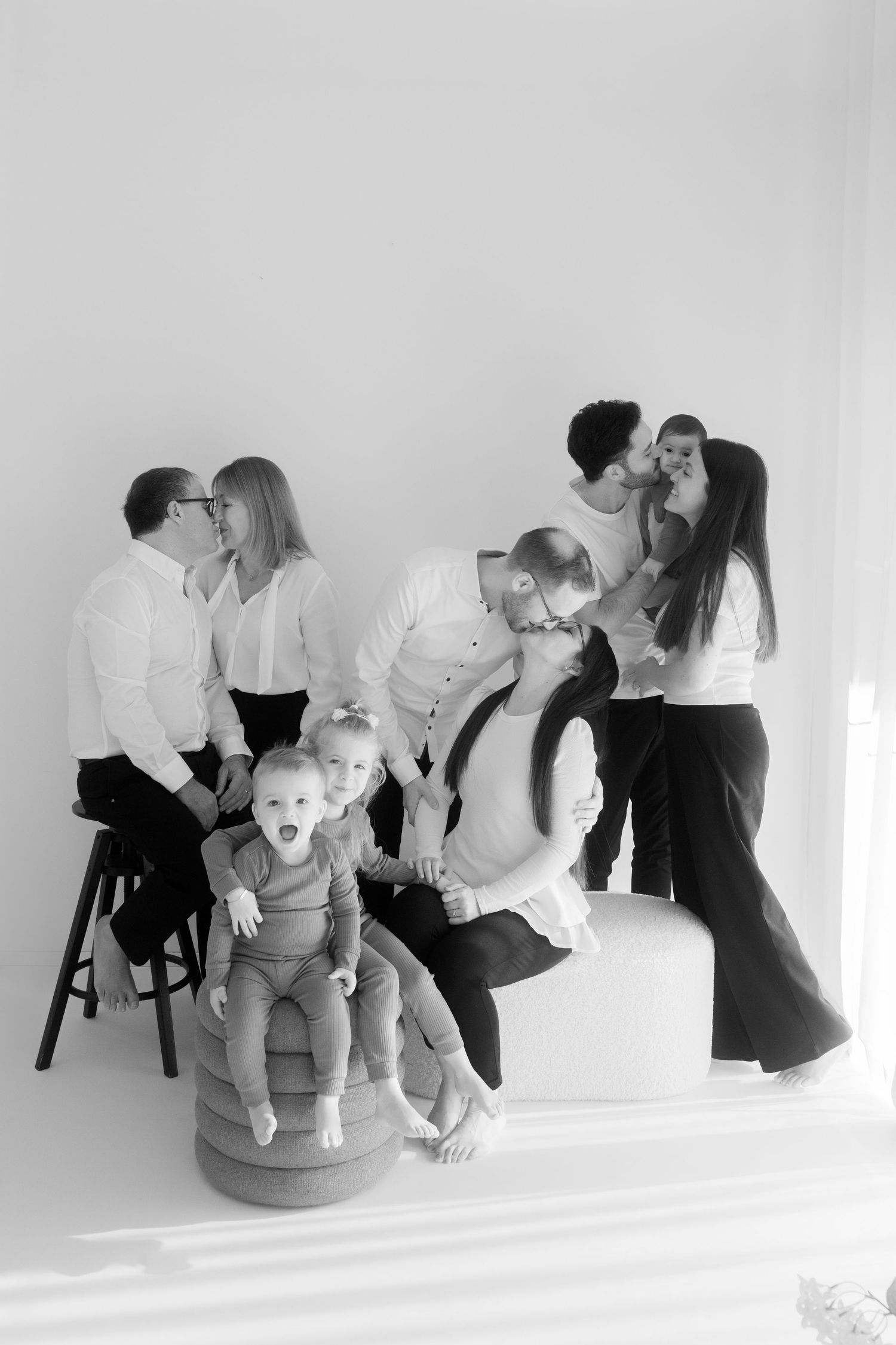 Intimate black and white portraits showing tender moments between parent and child on a simple wooden chair.