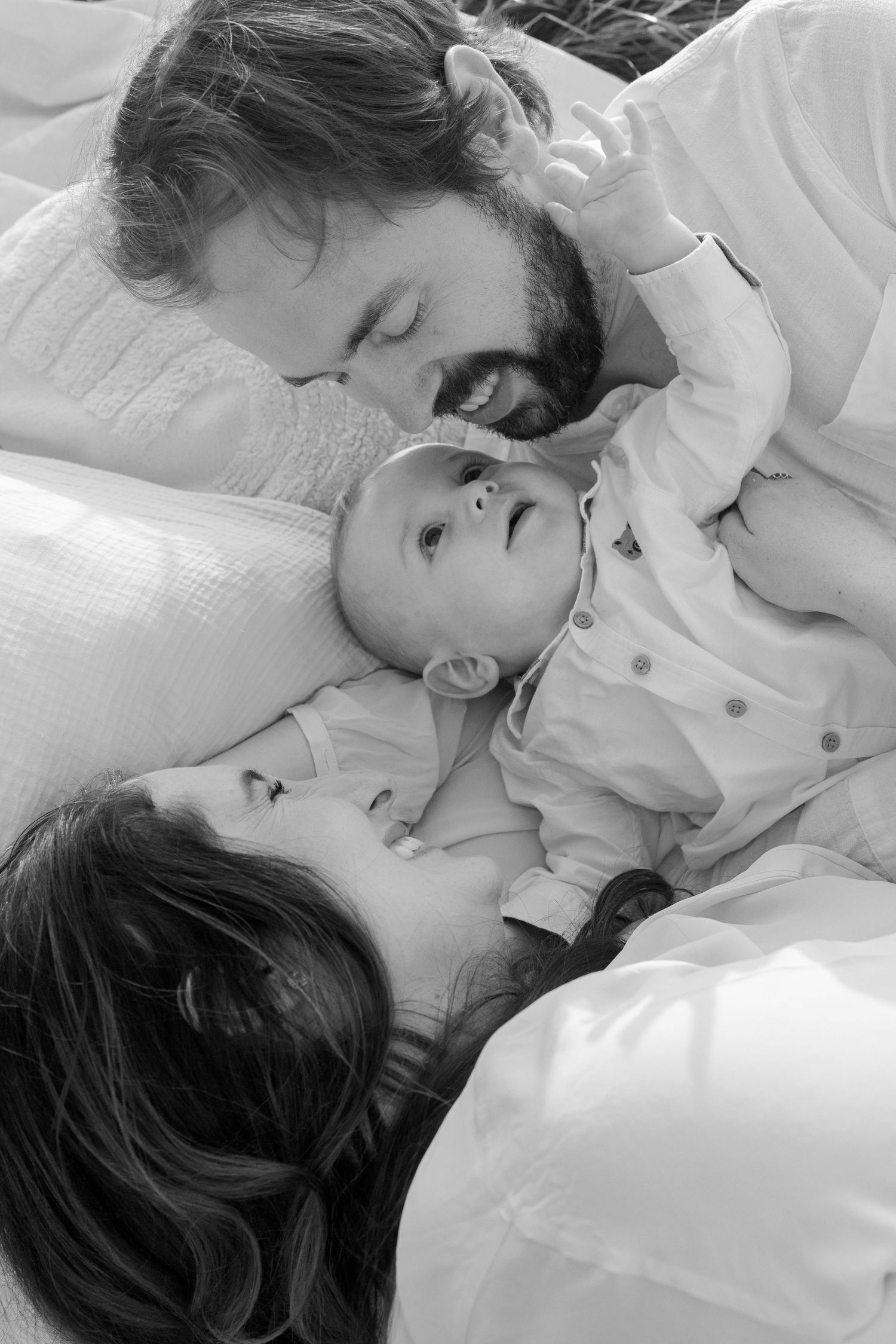 Intimate black and white portraits of family moments on white bedding.