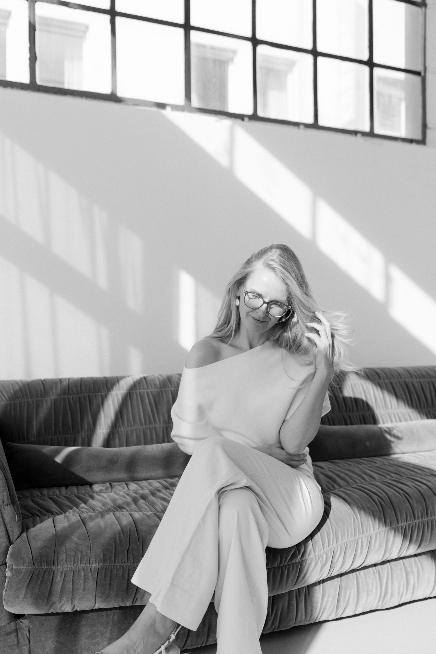 A black and white photo series shows a person in white clothing reclining and moving across a dark couch.