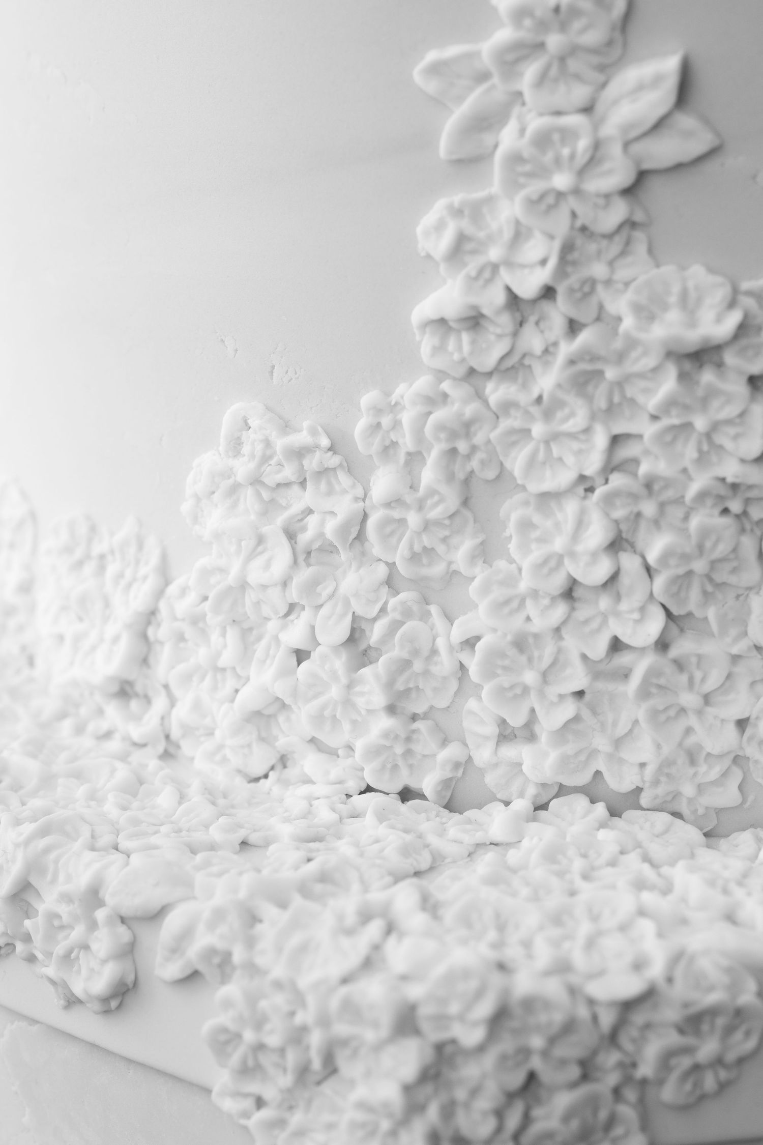 Close-up of an elegant white wedding cake adorned with intricate sugar flowers in a cascading floral design.