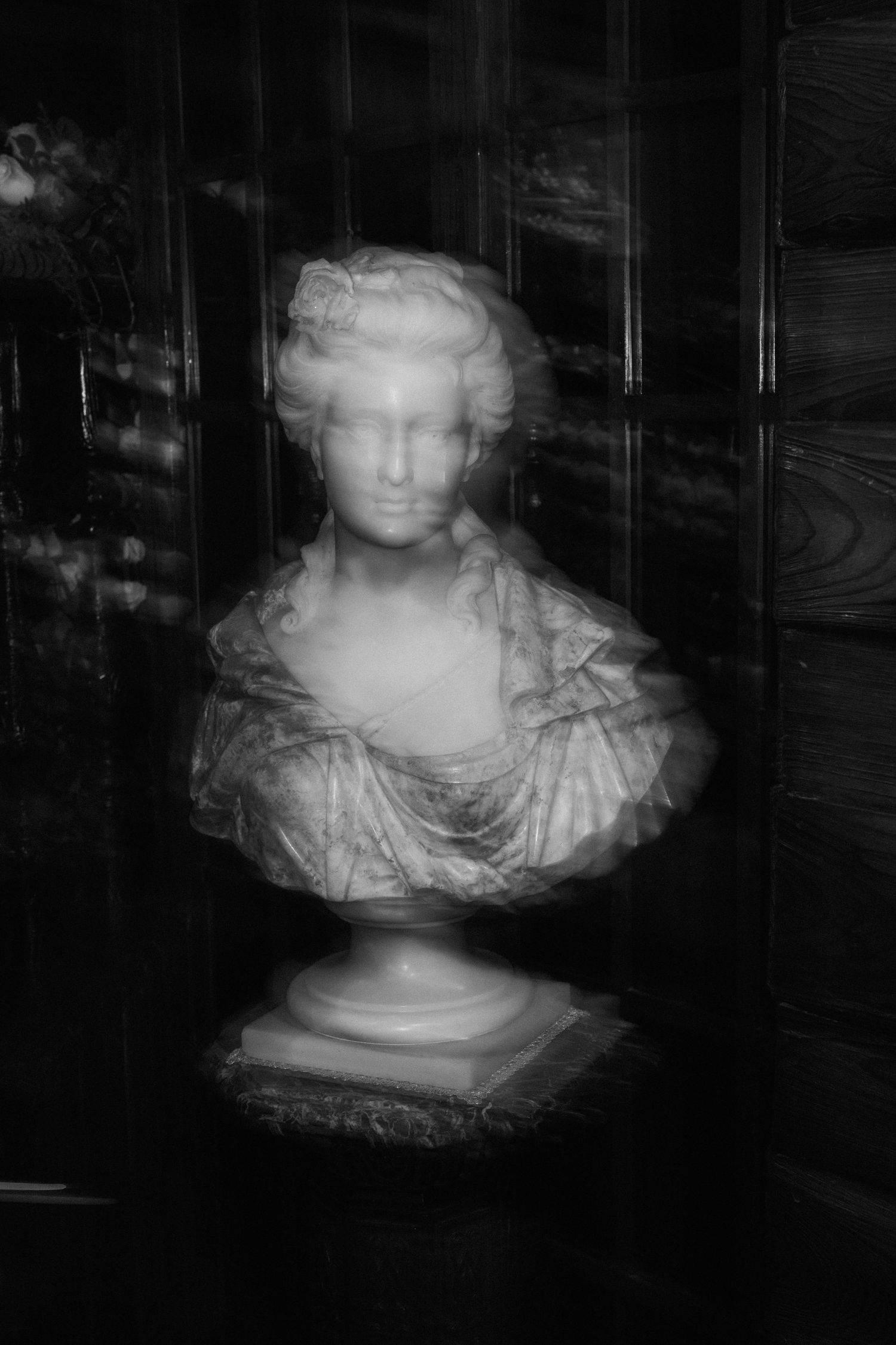 Classical marble bust sculpture photographed in dramatic black and white lighting.