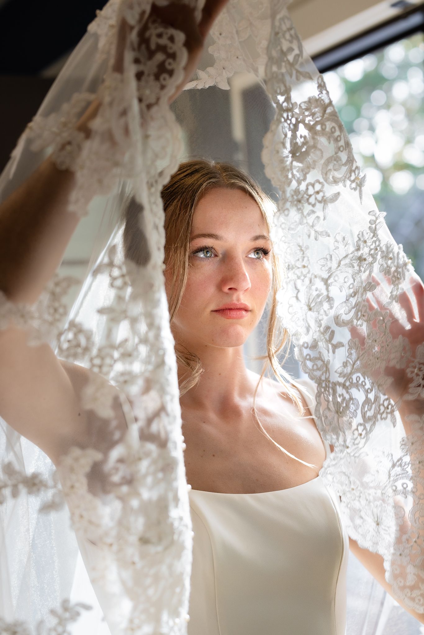 Editorial bridal portrait with bride beneath ethereal lighting holding Steven Khalil couture veil, captured by Chicago wedding photographer.