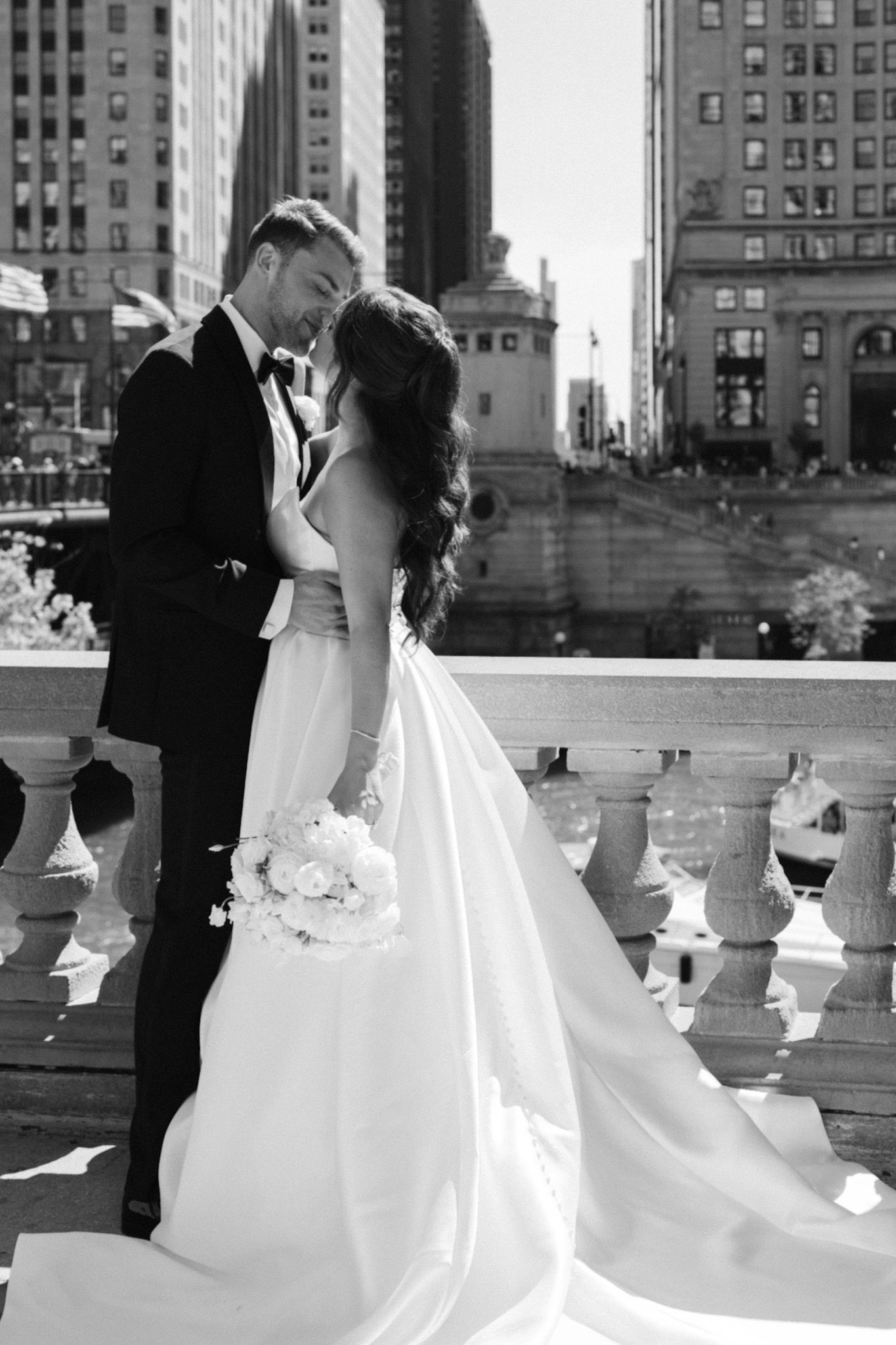 Stylish couple embracing and kissing on iconic Chicago bridge, bride wearing statement gown, photographed by Chicago wedding photographer.