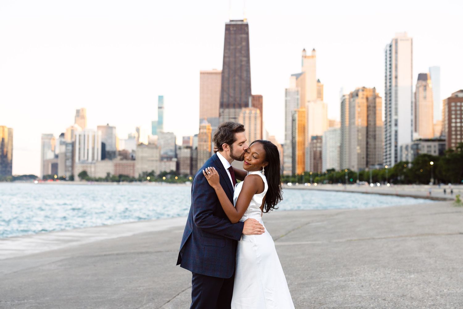 Chicago engagement session at North Avenue Beach featuring city skyline views. Engaged couple embracing at North Avenue Beach, downtown.