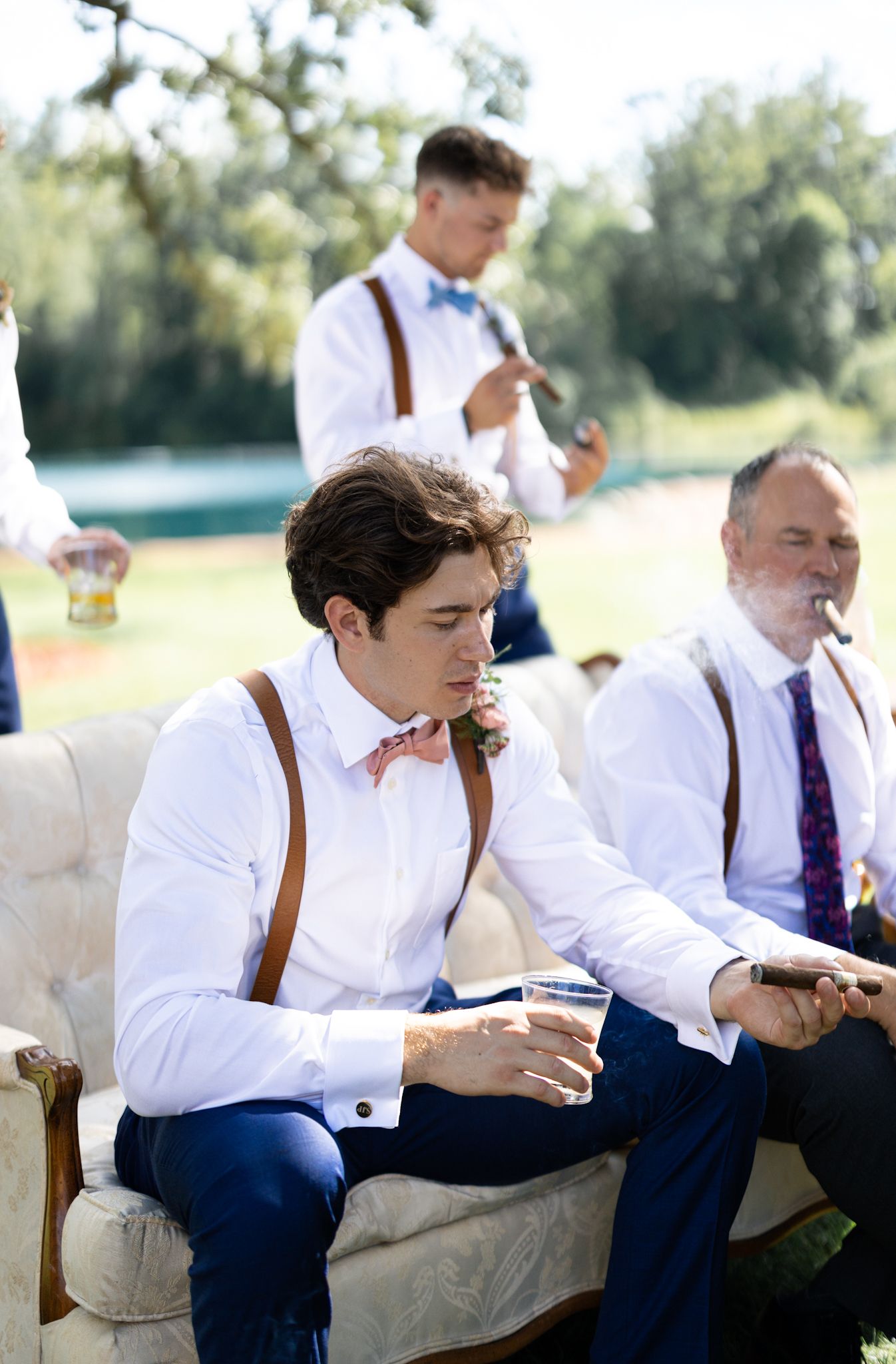 Groomsmen styled in suspenders and bow-ties with cigars are captured by a luxury Chicago documentary & editorial wedding photographer.