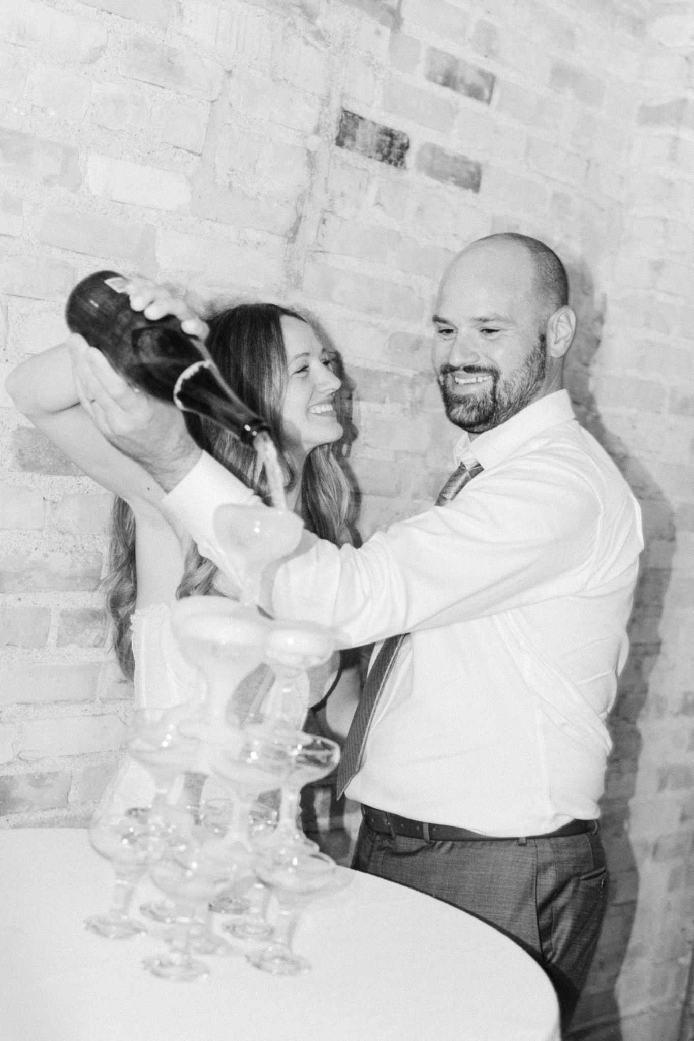 Bride and groom pouring champagne tower, captured by luxury Chicago wedding photographer in editorial documentary style for high-end wedding