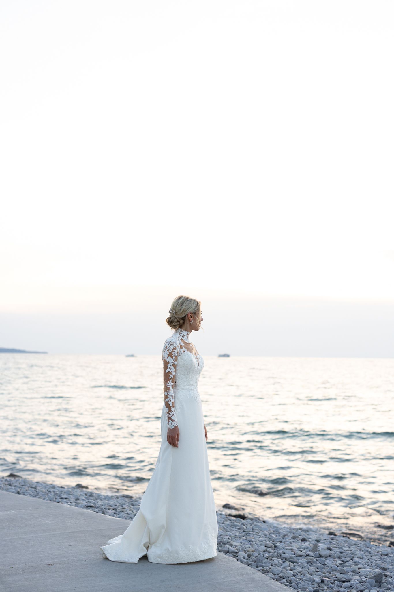 Bride in elegant gown overlooking Lake Michigan at Chicago planetarium, photographed in candid editorial style by top Chicago luxury wedding