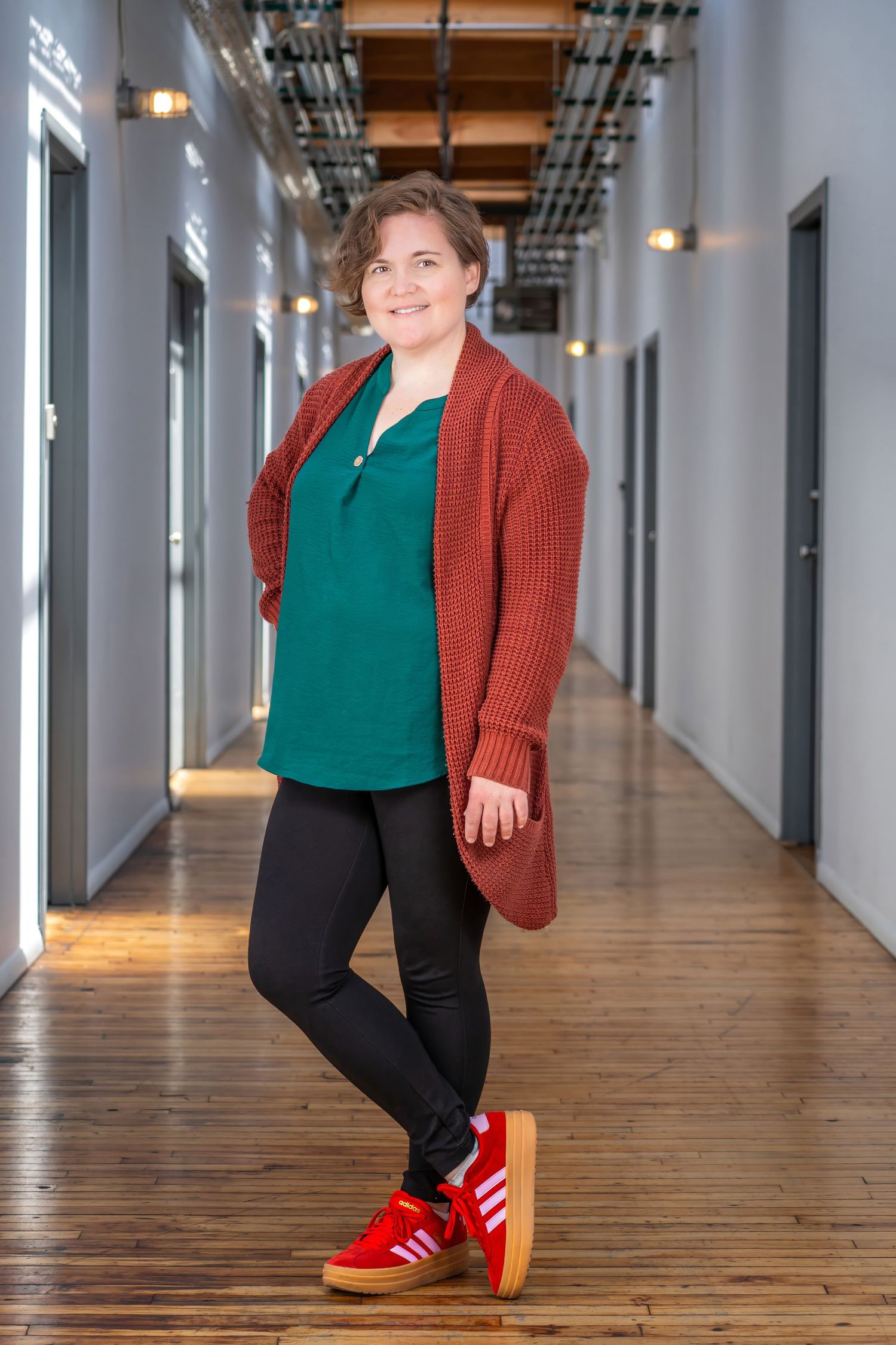 Full-length portrait of a woman in a red cardigan in a modern corridor