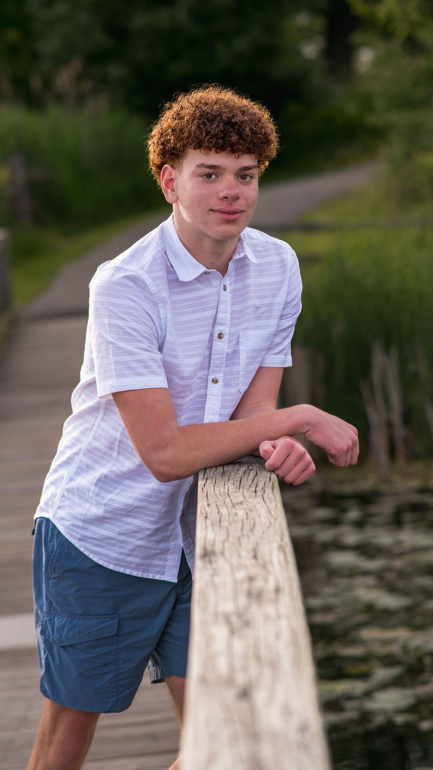 Teenage boy leaning on a wooden post outdoors, natural-light portrait