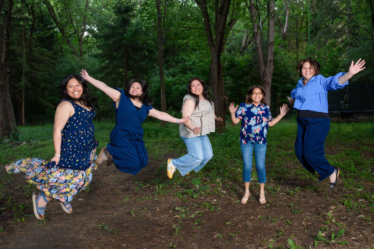 Family jumping and laughing together in a forest, fun family session