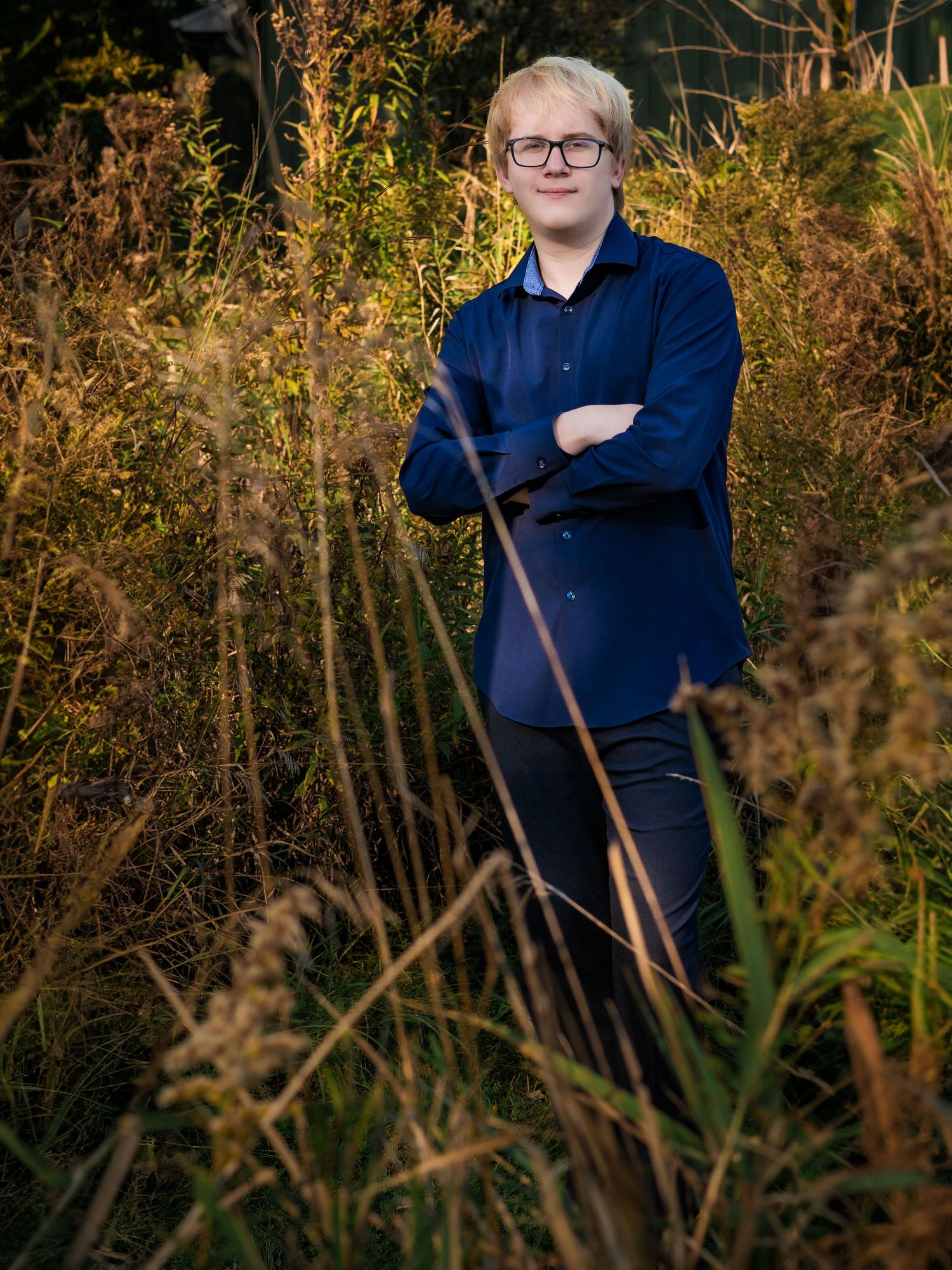 Senior portrait of a young man standing in a tall grass field