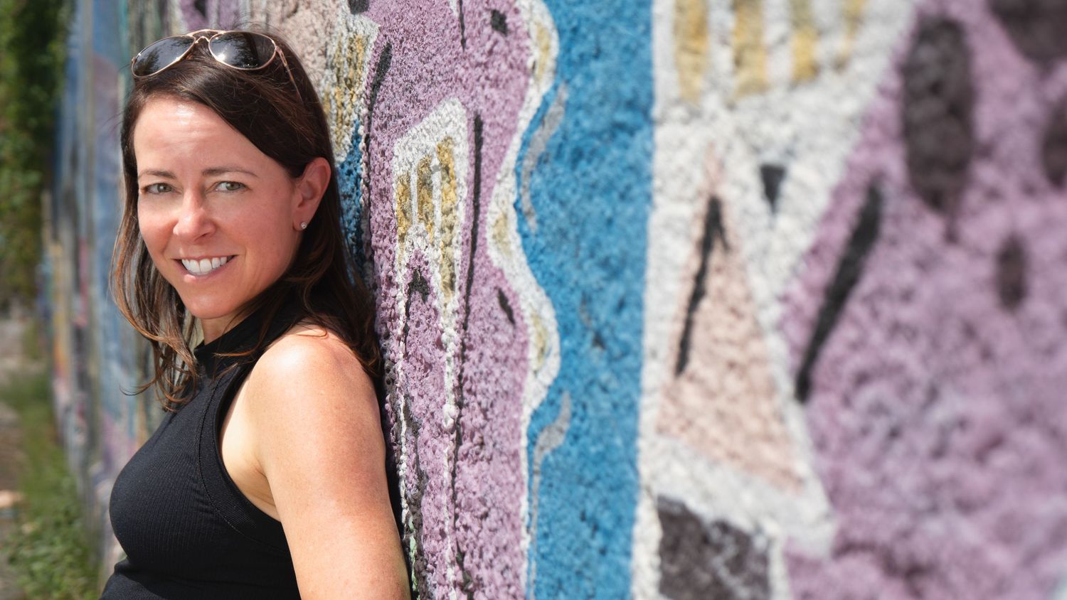 Portrait of a woman smiling beside a colorful mural