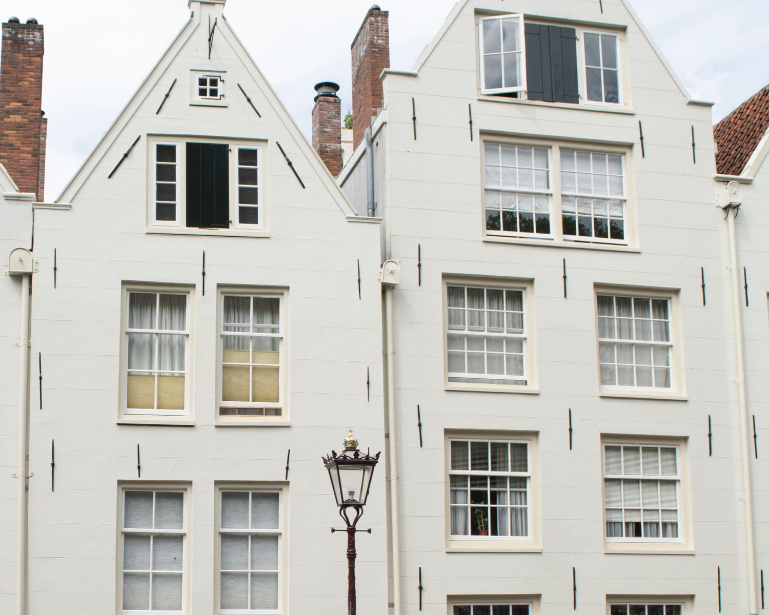 White Dutch-style canal houses with stepped gable roofs and large sash windows in Amsterdam, Netherlands.