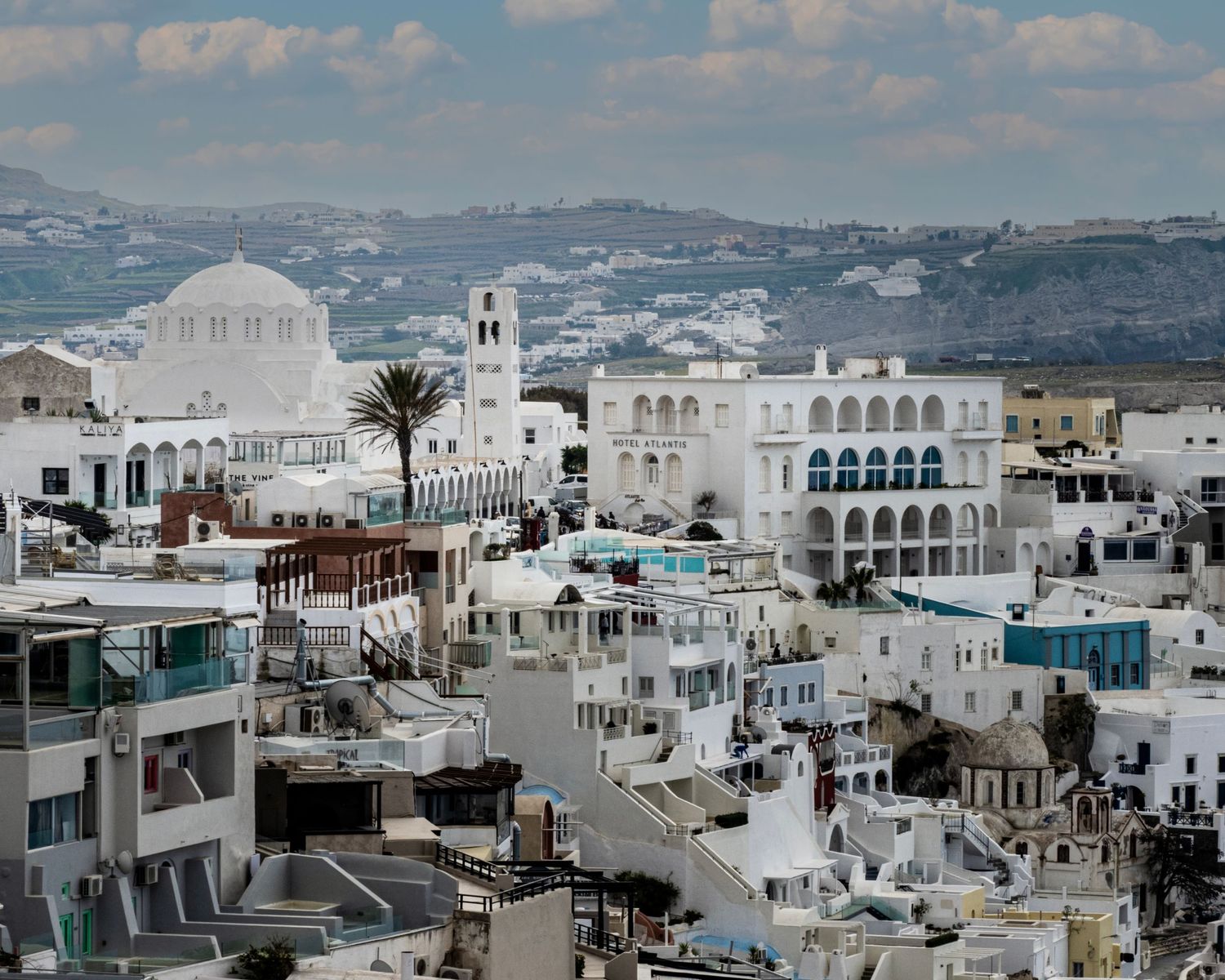 Aerial view of Santorini's white-washed buildings and domed church overlooking the caldera in Greece.