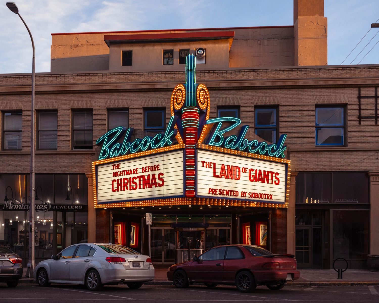 Babcock Theatre marquee lit up at dusk displaying The Land of Giants and Christmas shows in downtown Billings, Montana.