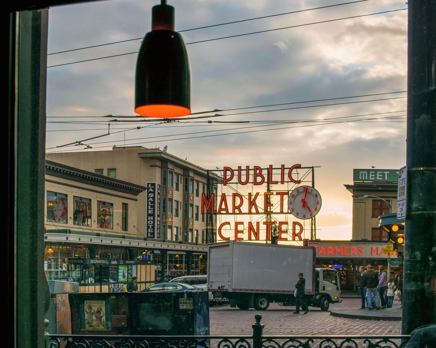 View from inside a cafe of the iconic Pike Place Public Market Center neon sign at dusk in Seattle, WA.