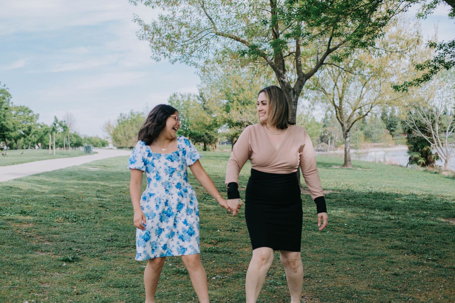 Two people share a happy moment while walking together on a grassy area in a park on a sunny day.