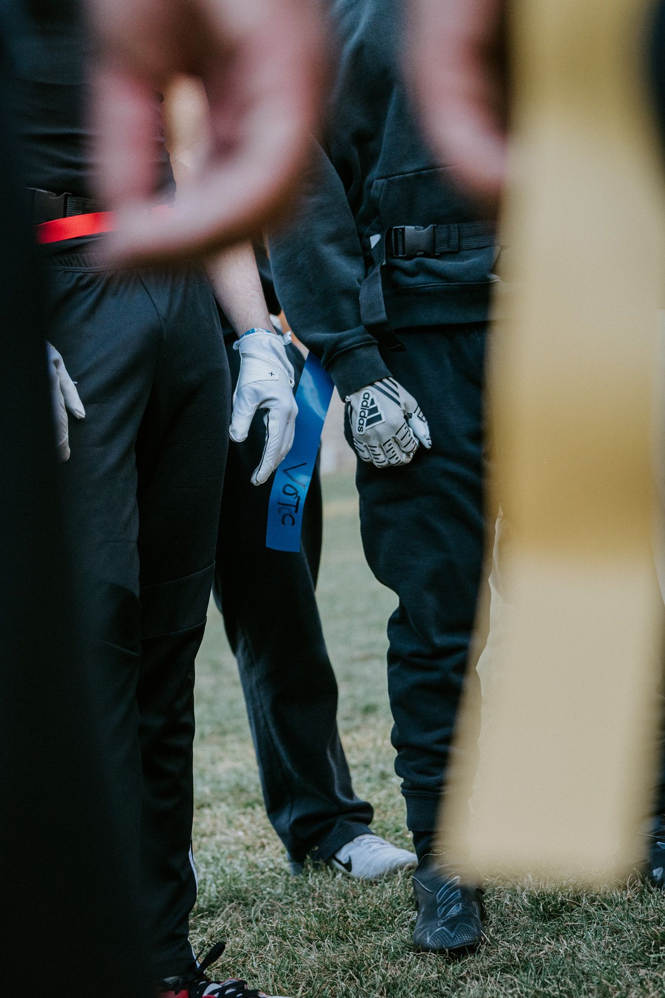 Professional in dark uniform pants wearing protective gloves while standing on grass during event.