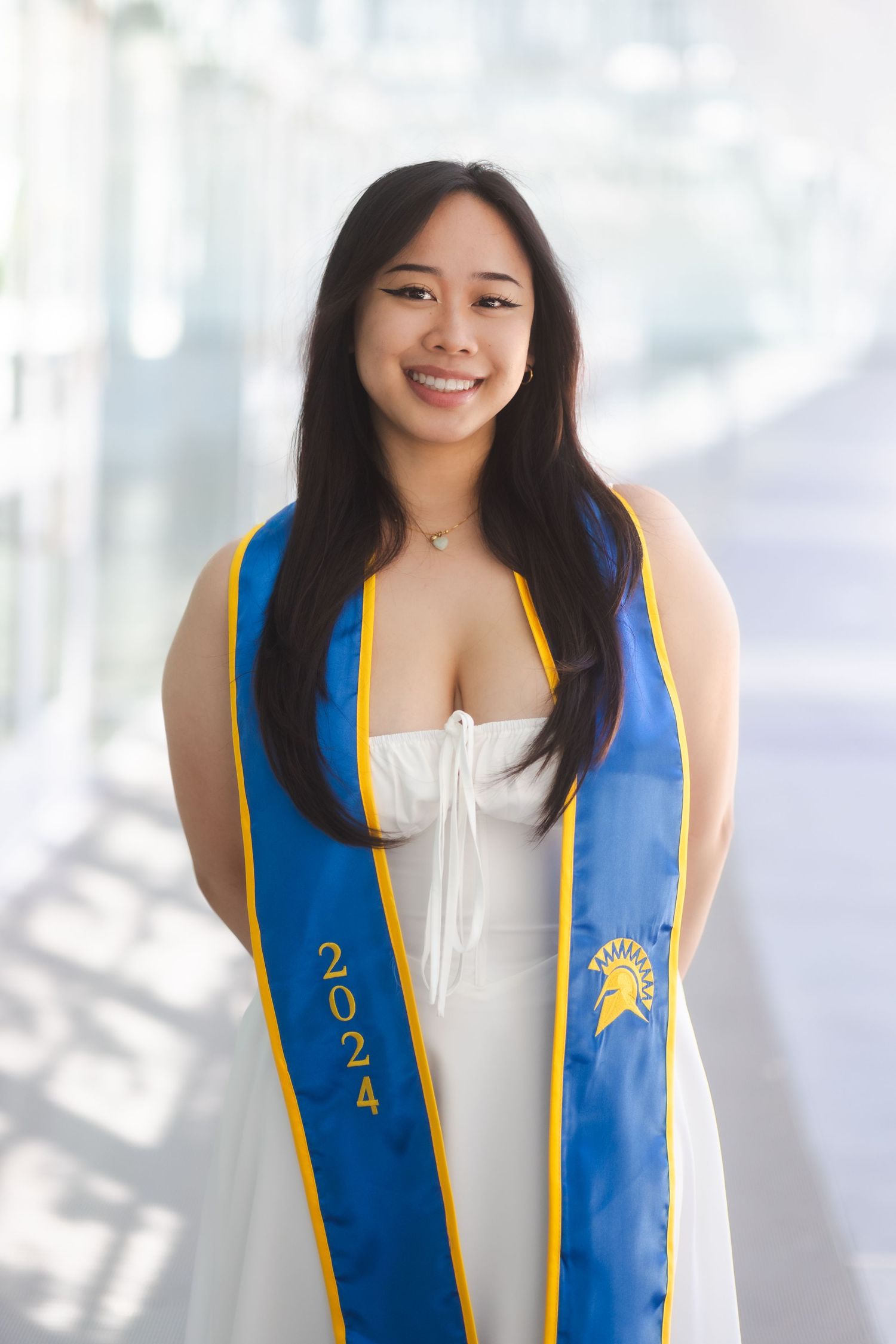 College graduation photo of a woman standing on a grassy hill in the Bay Area, photographed by a Bay Area portrait photographer.