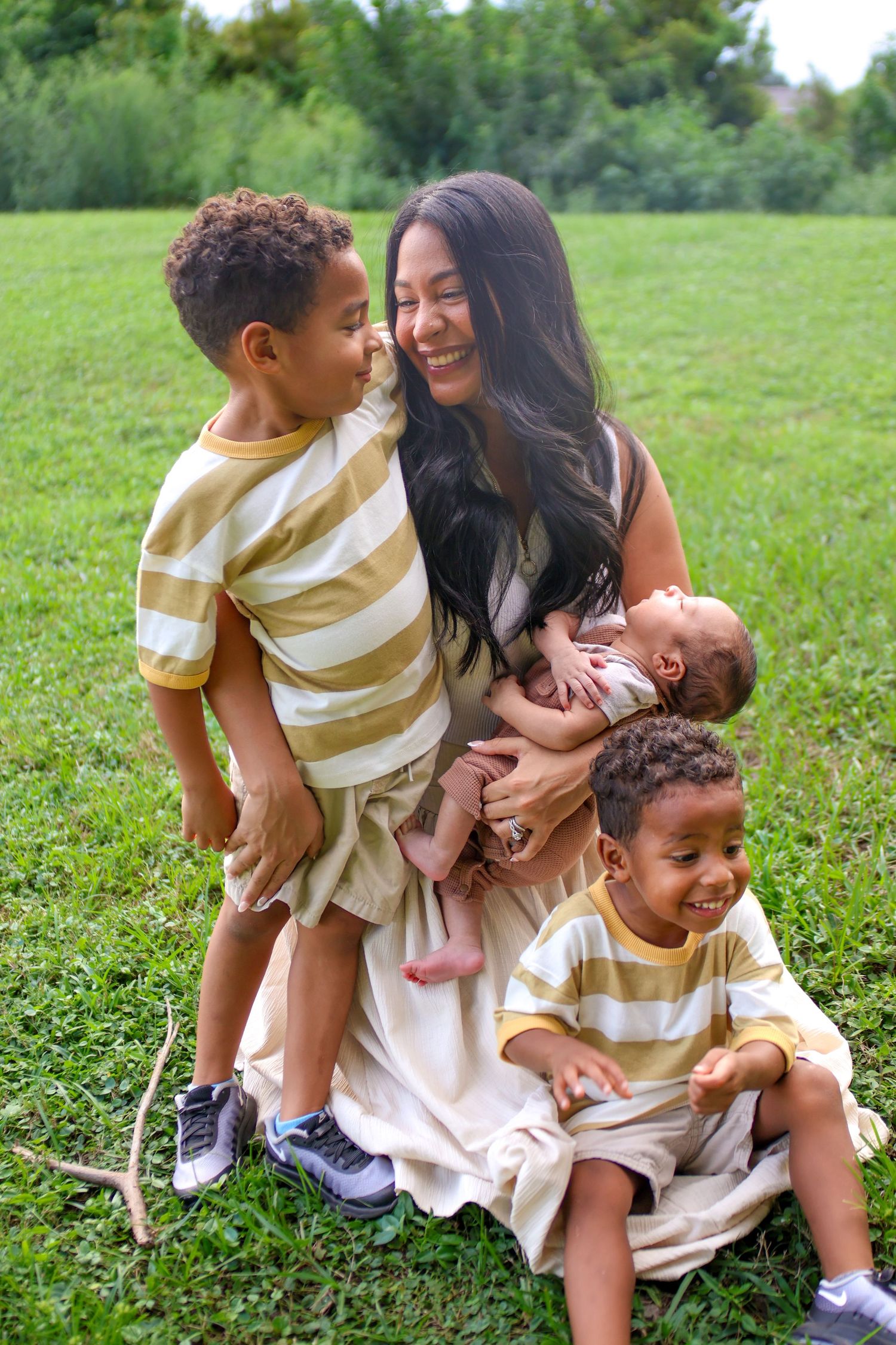 mother admiring oldest son while holding newborn and middle child playfulness in oviedo, Florida for family portrait photography