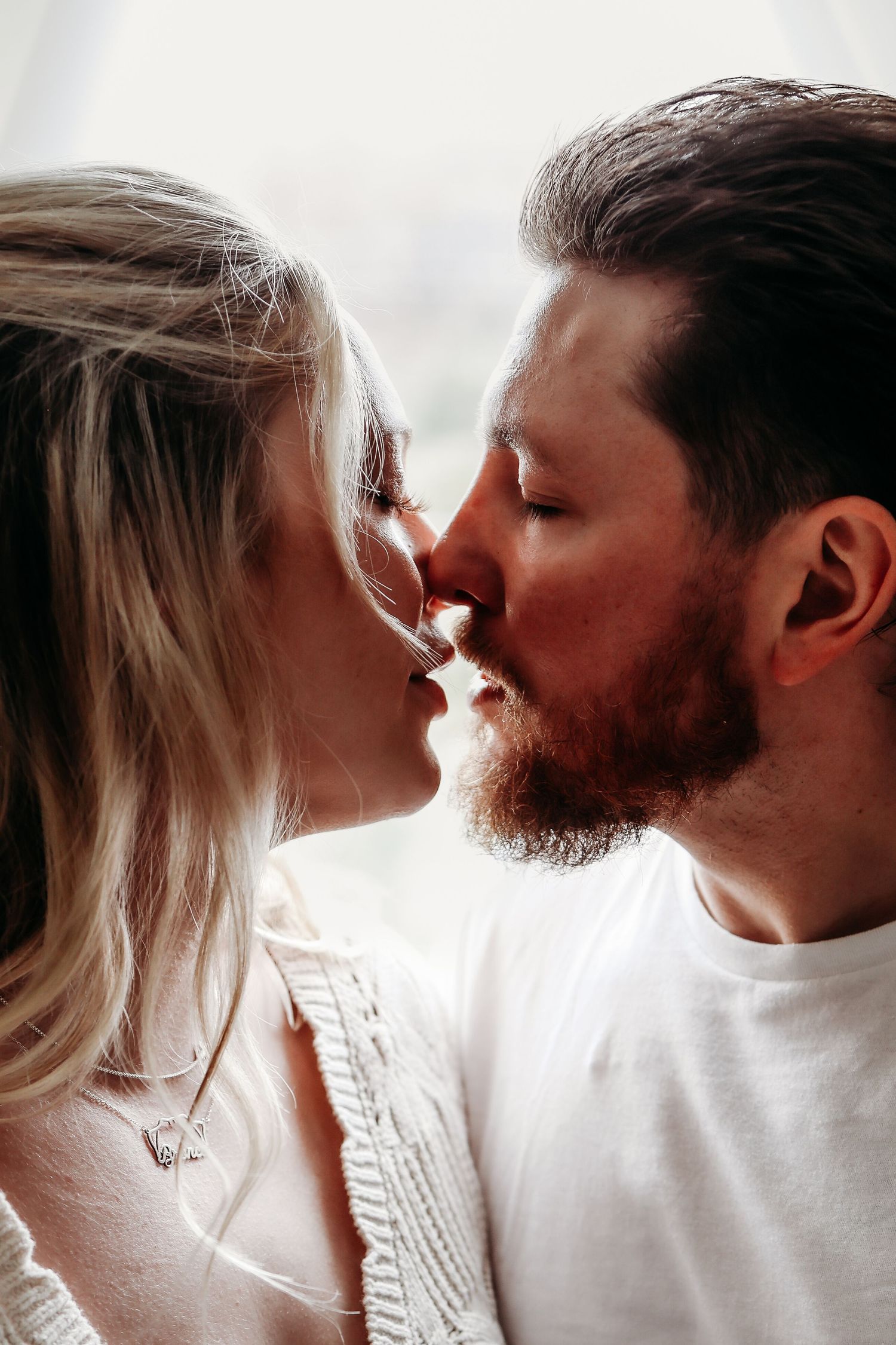 A romantic couple in white clothing share intimate moments in a series of close-up photographs.